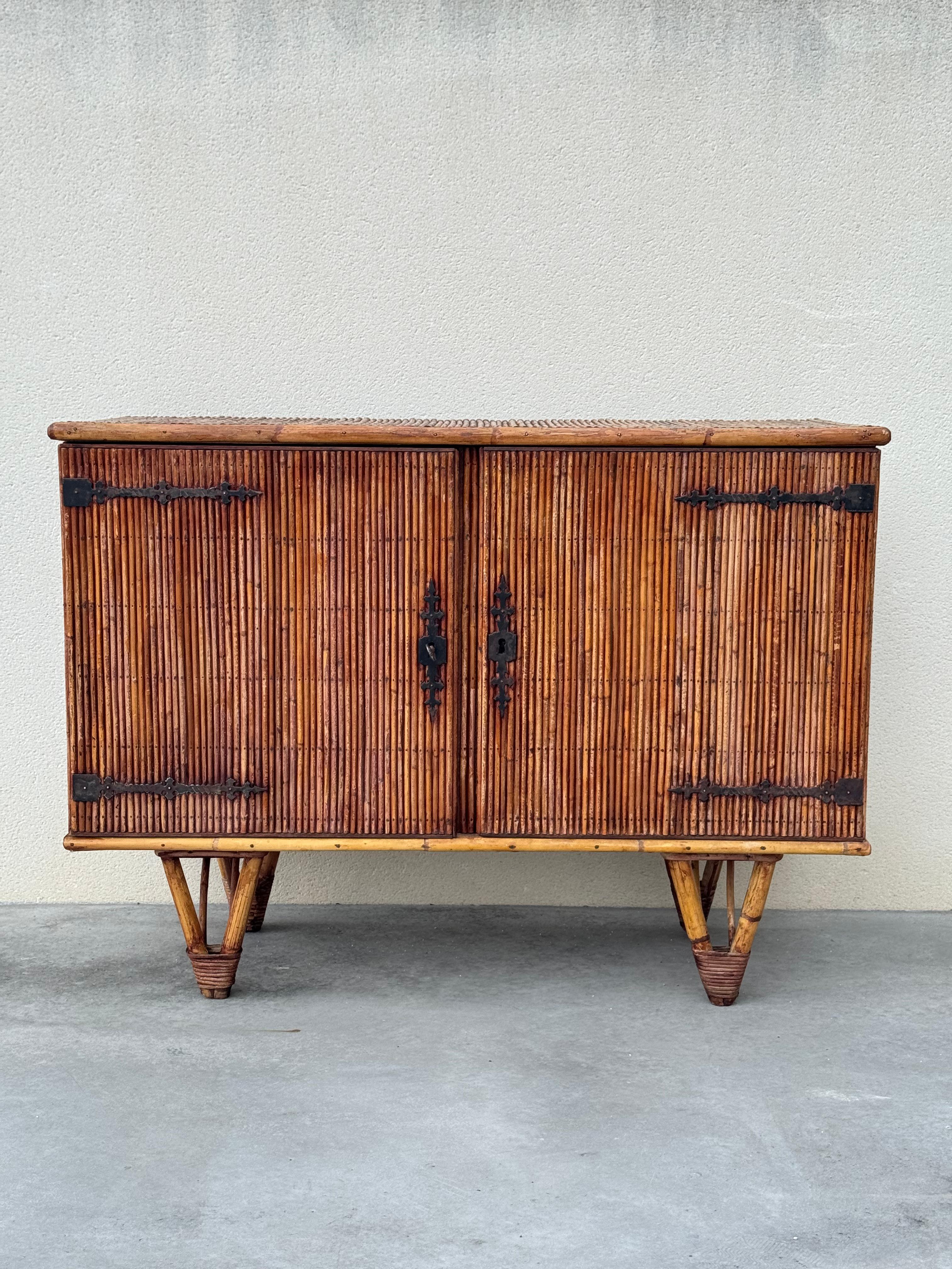 Beautiful rattan bamboo sideboard by Adrien Audoux and Frida Minet . 

Two-door cabinet with intricate wrought iron hinges with original key, two interior shelf. 
Thick bamboo legs with wrapped rattan detail. 

Original finish shows varying shades