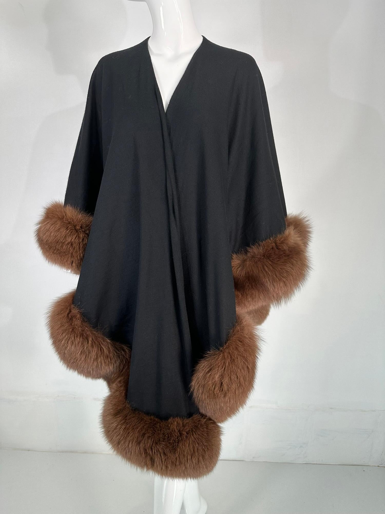 Cape/wrap Adrienne Landau en laine noire bordée de zibeline, datant des années 1990. Une belle cape/enveloppe parfaite pour les événements de jour ou de soirée. Cette cape en laine chaude est facile à porter. Elle est ouverte sur le devant, plus