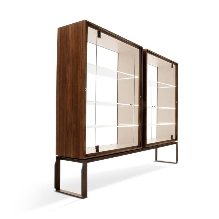 A collection that expresses uniqueness and harmony, always and everywhere.

Glass cabinet in walnut Canaletto wood (fin.11) made up of two vertical elements. The interior is available in white painted Fiddleback Sycamore. The doors, back, and