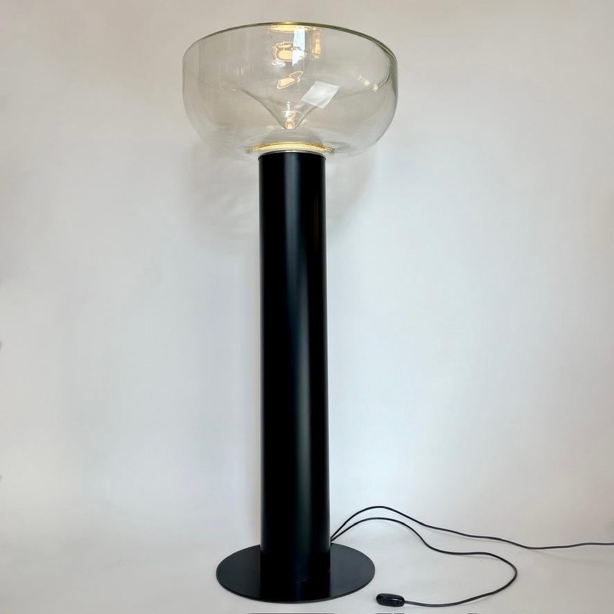AELLA floor lamp a stunning must have collectible, born from the creative minds of designers Renato Toso and Giovanna Noti Massari in 1968. With a longer matte black extruded aluminum body compared to the smaller and shorter table version, this lamp