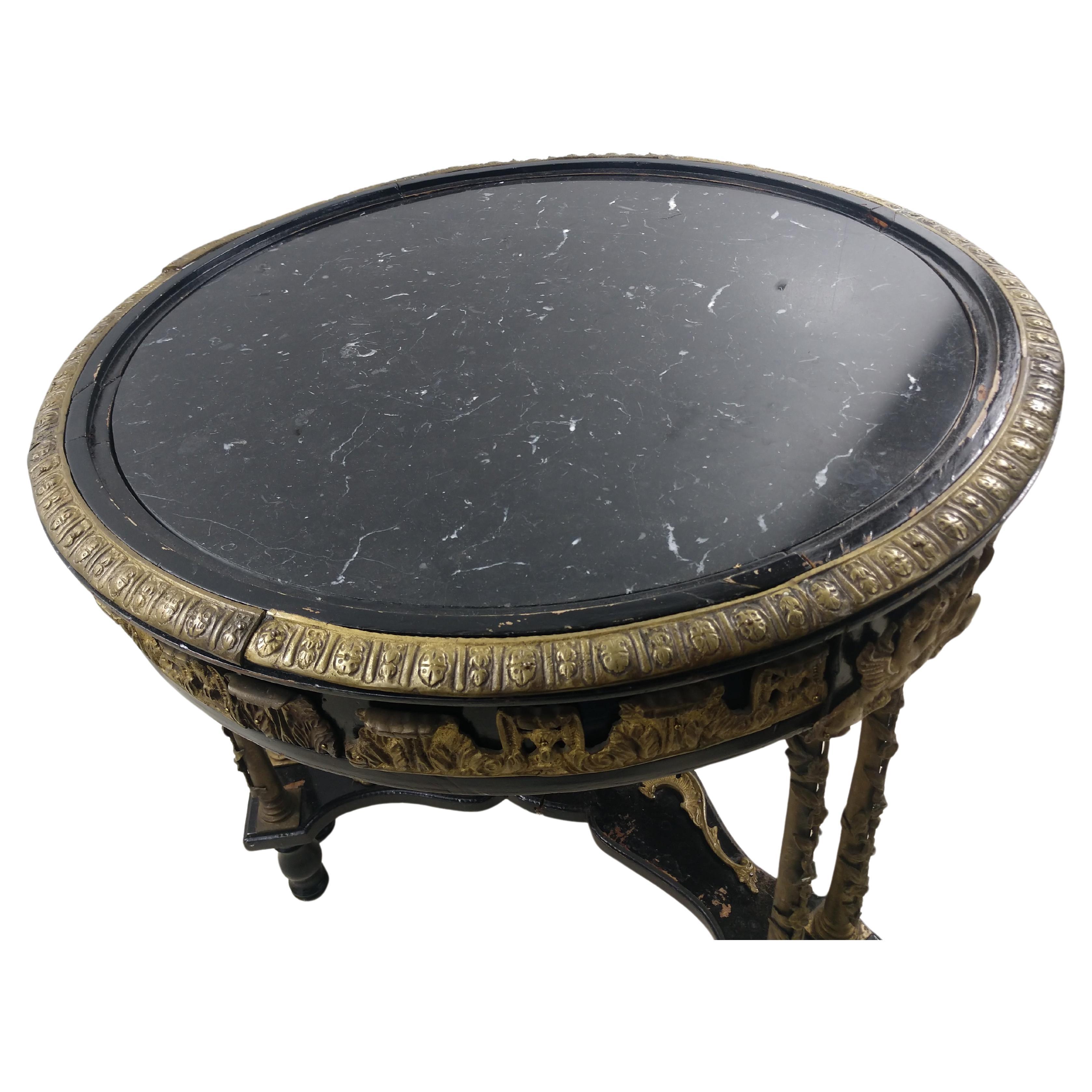 Fabulosa mesa con tablero de mármol negro y cubierta con bellos adornos de bronce fundido. El mármol está engarzado en la parte superior, y montado con un borde de bronce. Falta un adorno de bronce en una pata de camilla. En la foto.