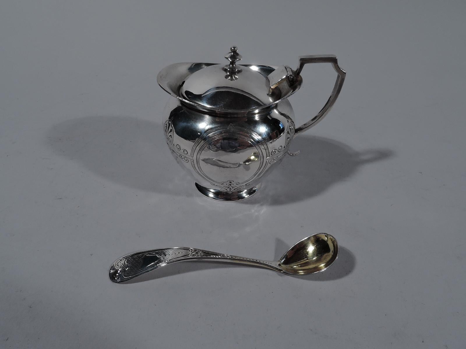 Aesthetic coin silver mustard pot with ladle, circa 1860. Pot: ovoid bowl with scroll-bracket handle and round flat foot. Flared rim and hinged and domed cover. Ladle: Curved and tapering shaft with oval gilt-washed bowl. Chased and engraved