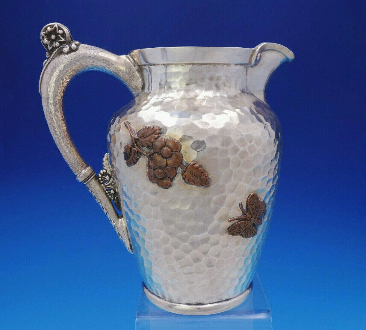 Gorham

Museum quality mixed metals Gorham sterling silver water pitcher #740. It is adorned with applied copper elements including flowers, an applied copper butterfly, applied large stork/egret/bird in flight, and applied copper cattails. There