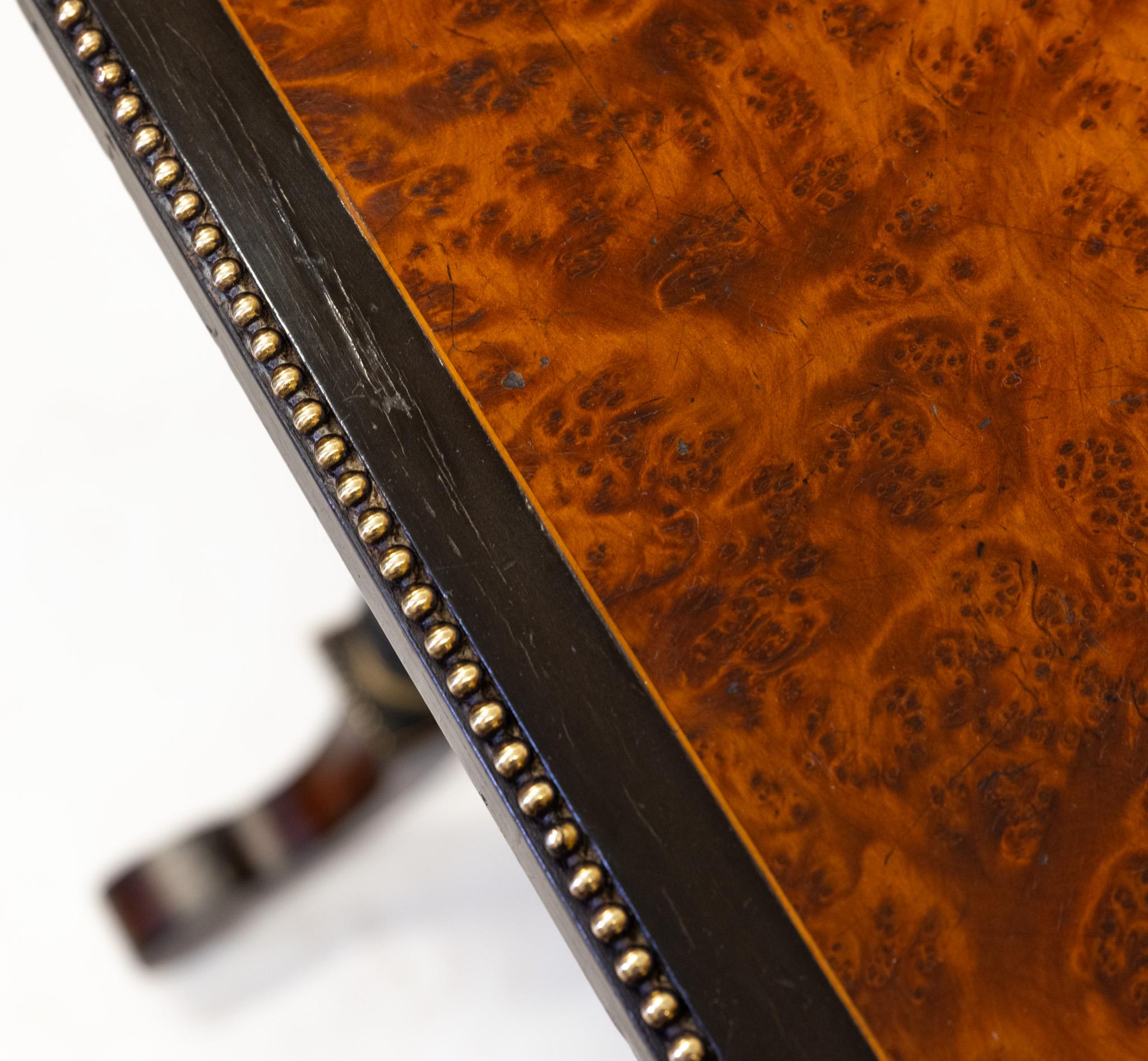 An Aesthetic Movement period amboyna burl, ebonised and gilt metal side table. English. Circa 1870.

The table having decorative veneered amboyna burl to the top and tier - the name amboyna derived from Ambon Island in Indonesia, where much of the