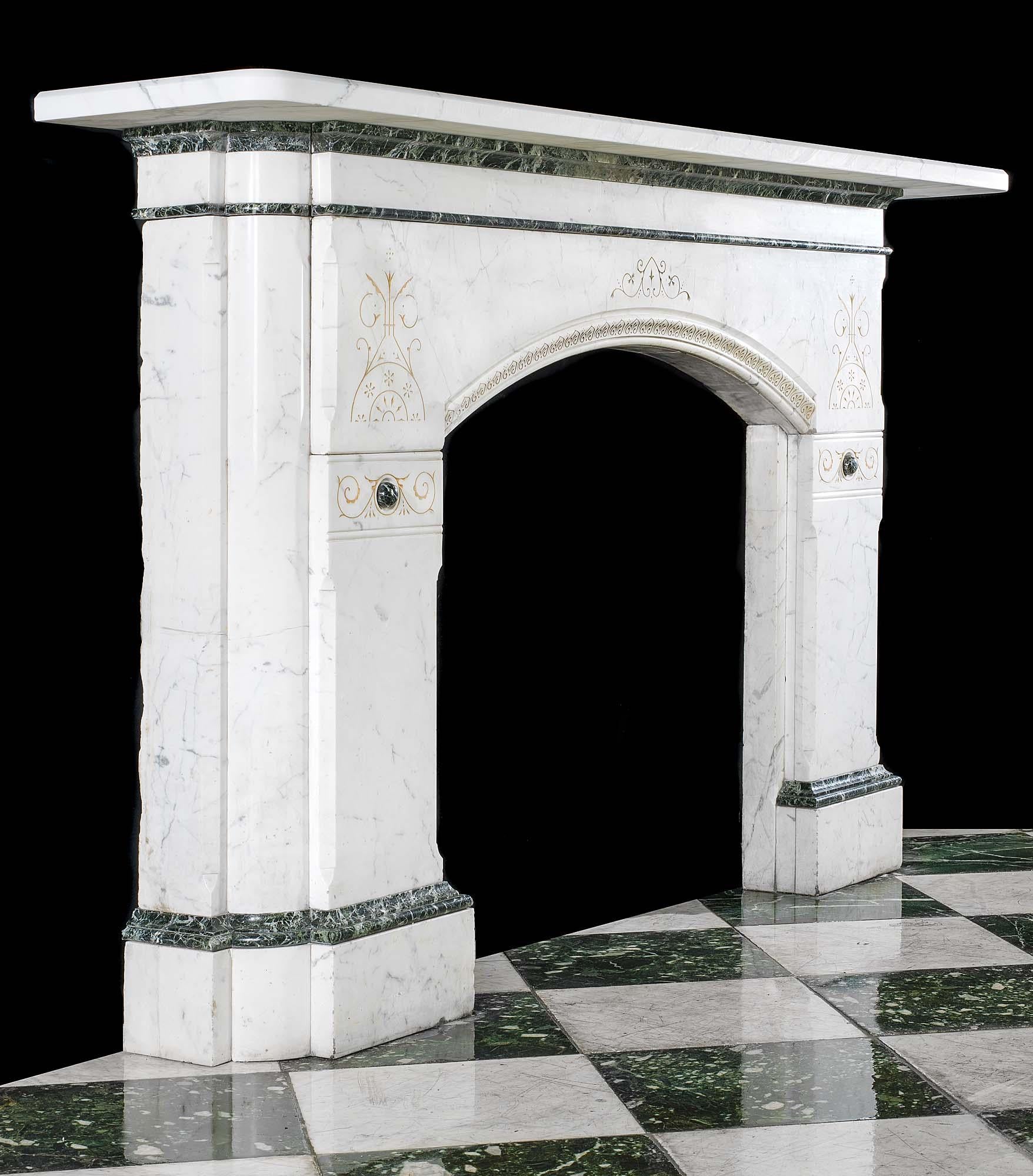 Eine elegante und große, an die Reformgotik grenzende, antike Kamineinfassung aus Bleistiftmarmor mit einem breiten, profilierten Regal. Der Hauptteil des Kamins, der mit Bändern aus Tinos-Verde-Marmor eingefasst ist, wird durch fein geschliffene
