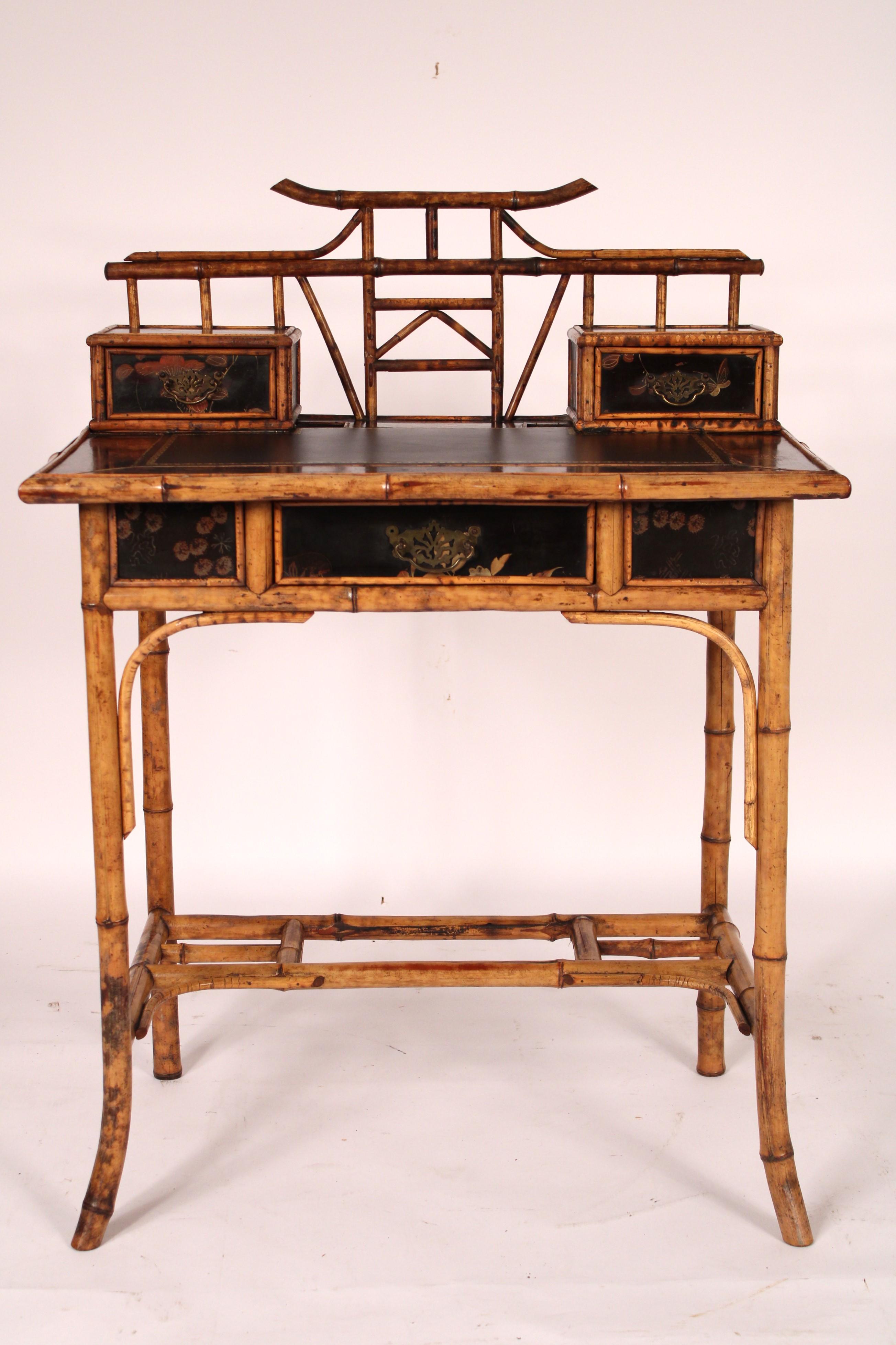 Aesthetic movement bamboo and lacquer writing table, circa 1910. With an Asian style bamboo top, the writing area with two small drawers on each side a later tooled leather top, a frieze drawer, resting on bamboo legs with bamboo stretcher bar.