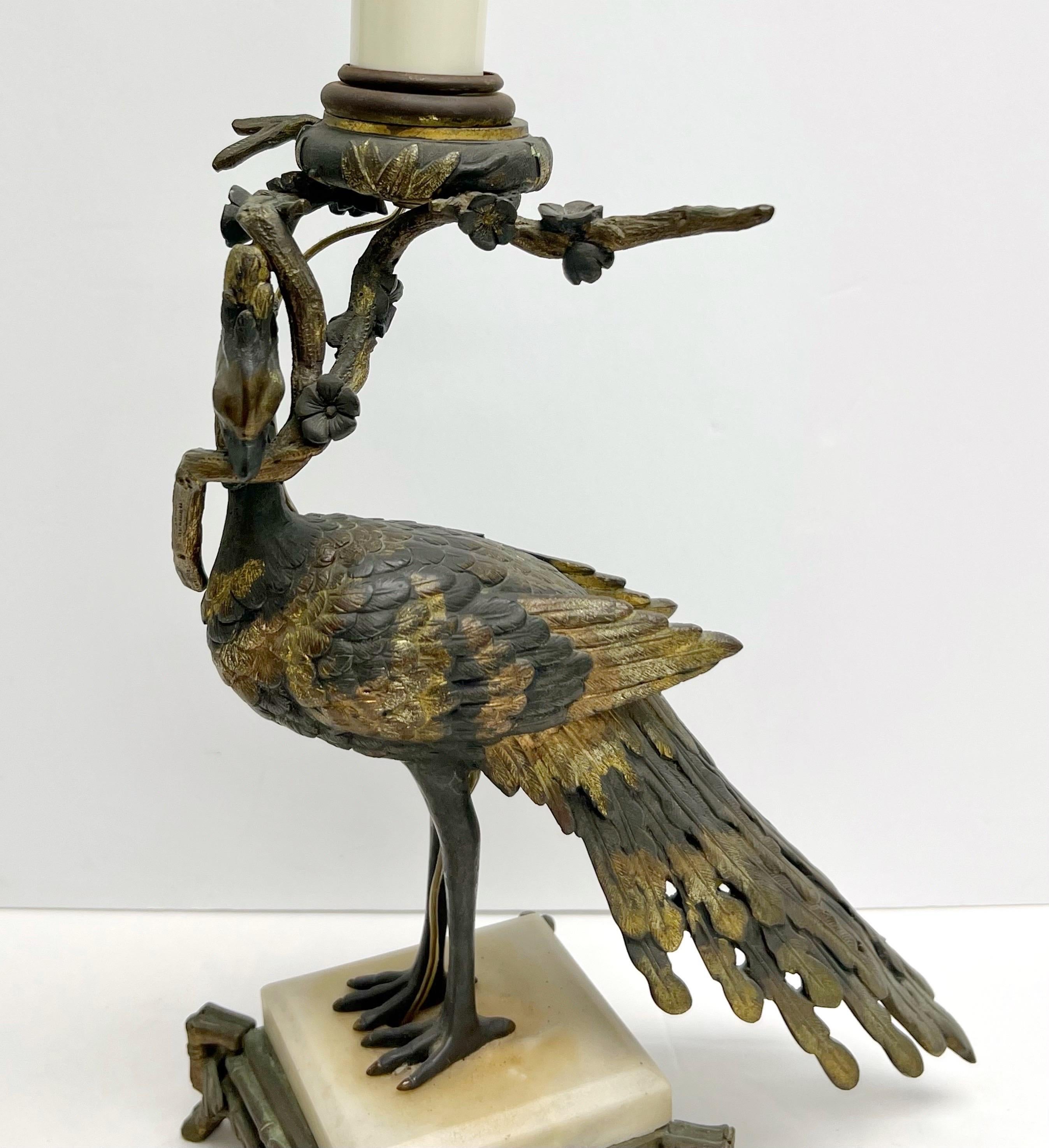A highly ornamental table lamp with a peacock holding a branch. 