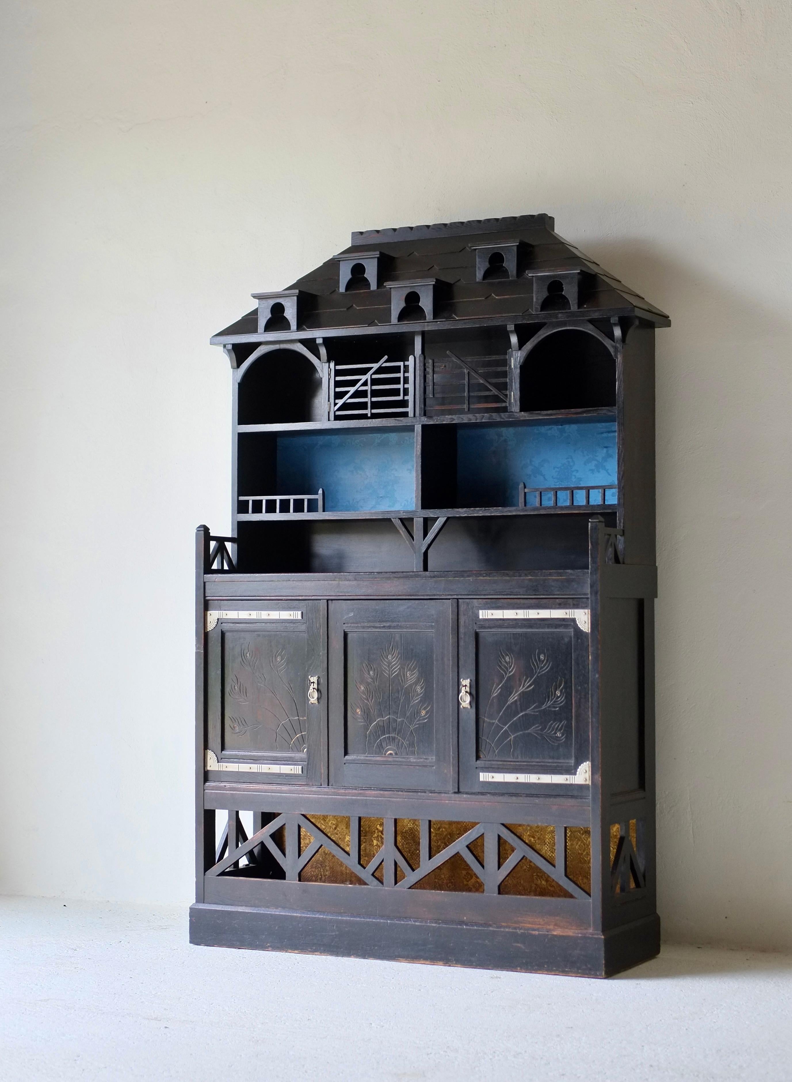 An Aesthetic Movement architectural cabinet in the manner of Charles Eastlake.

English, circa 1880.

Ebonised oak, incised gilded decoration with applied silk, copper and white metal fittings.

In very good condition.

H 202.5 W 121.5 D 41 cm