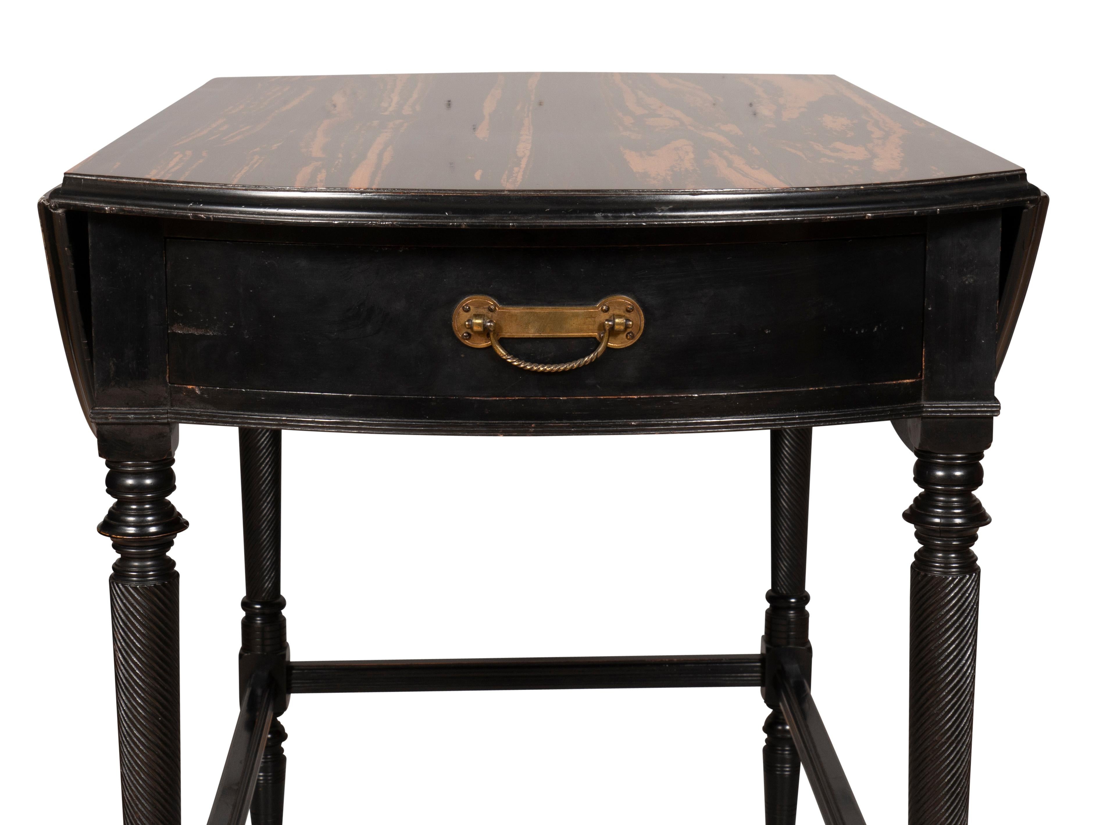 Finely constructed with Calamander wood top with D shaped hinged drop leaves over a frieze drawer with a nicely cast bail handle , the opposing end with false drawer, raised on ebonized finely carved spiral tapered supports joined by a box