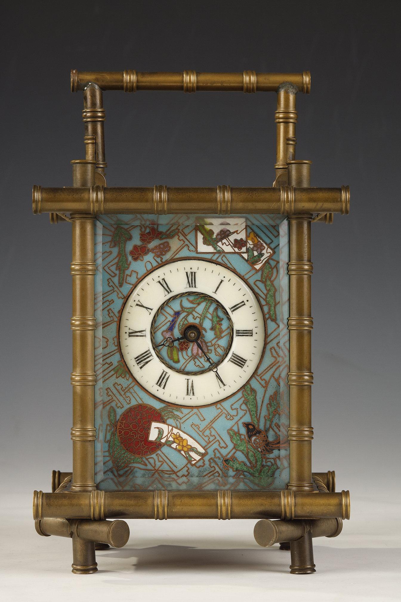 Fine aesthetic movement clock in cloisonné enamel and gilded bronze, decorated with polychromed birds and flowers, and geometric gilded ornaments on a blue ground. The dial is covered by a beveled glass and the gilded bronze sides of the clock
