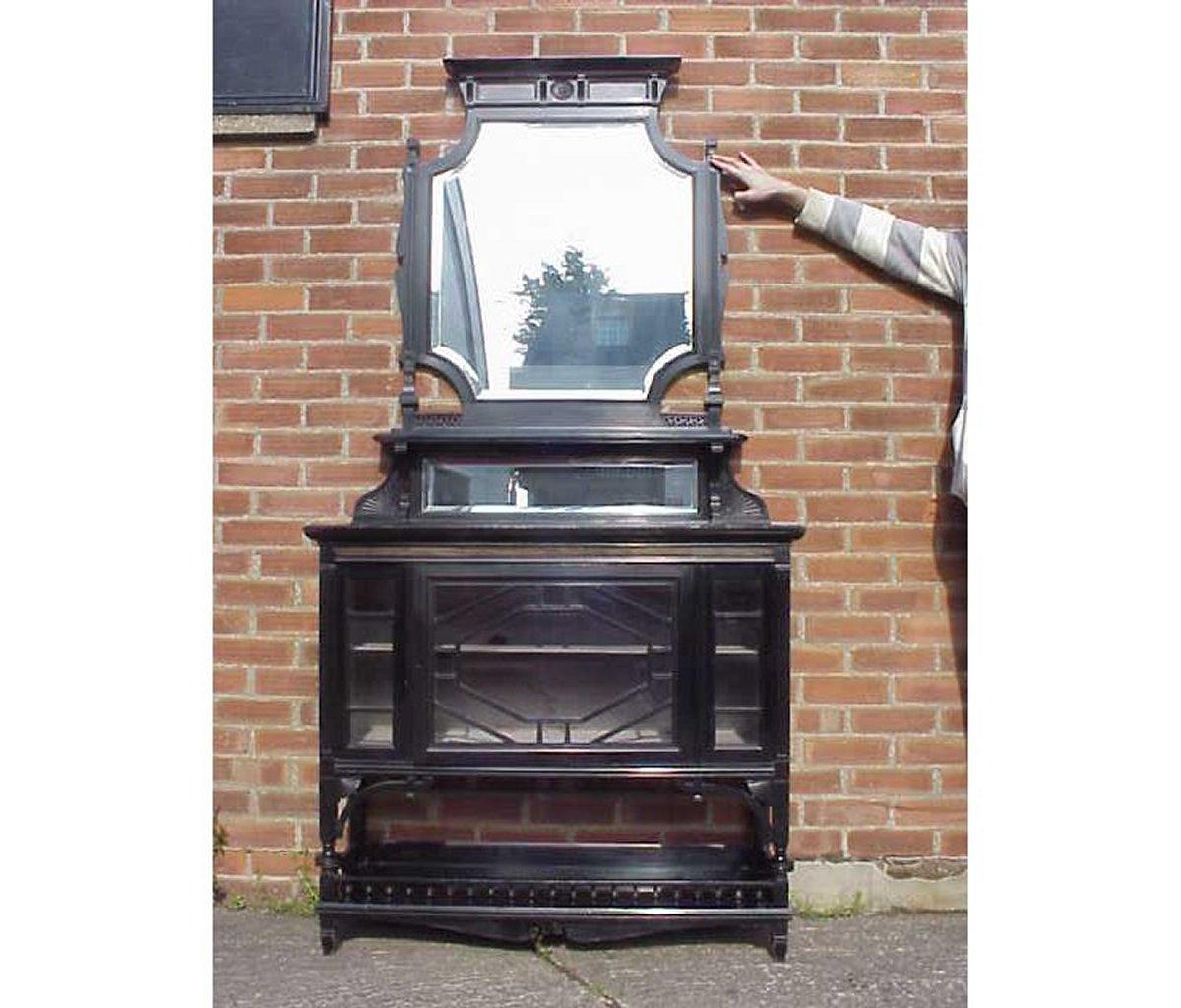 Lamb of Manchester, an Aesthetic Movement ebonised and coromandel side cabinet, with a bevelled mirrored and shelved back, a glazed base with a spindle galleried undershelf, stamped to top edge of door.
Possibly designed by W. J. Estall. Lambs were
