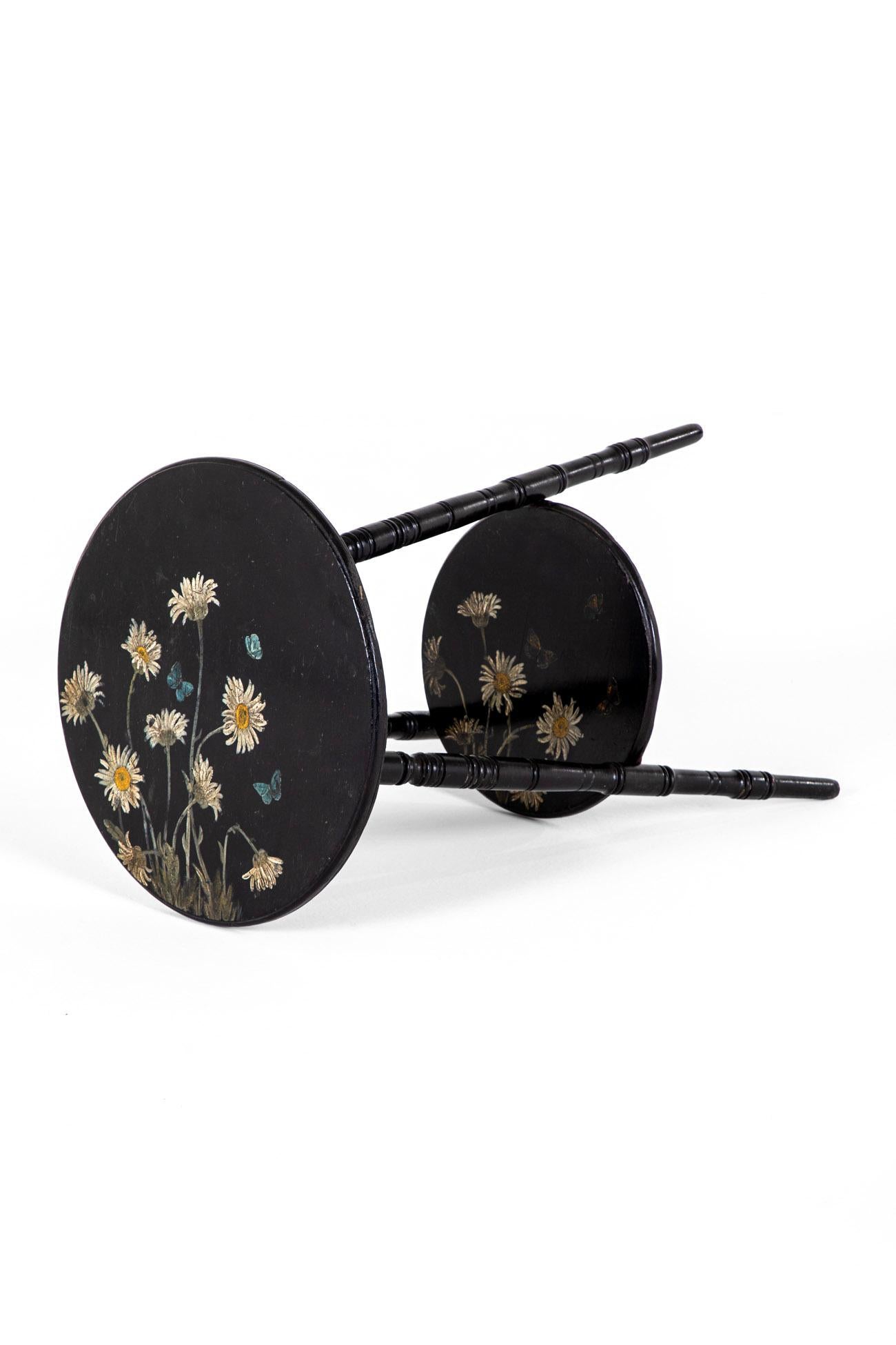 A wonderful Aesthetic Movement ebonised occasional table with a circular top and lower tier.

Both tiers are beautifully painted in the original Victorian penwork designs with floral motifs and butterflies.

Three graduating turned legs connect the