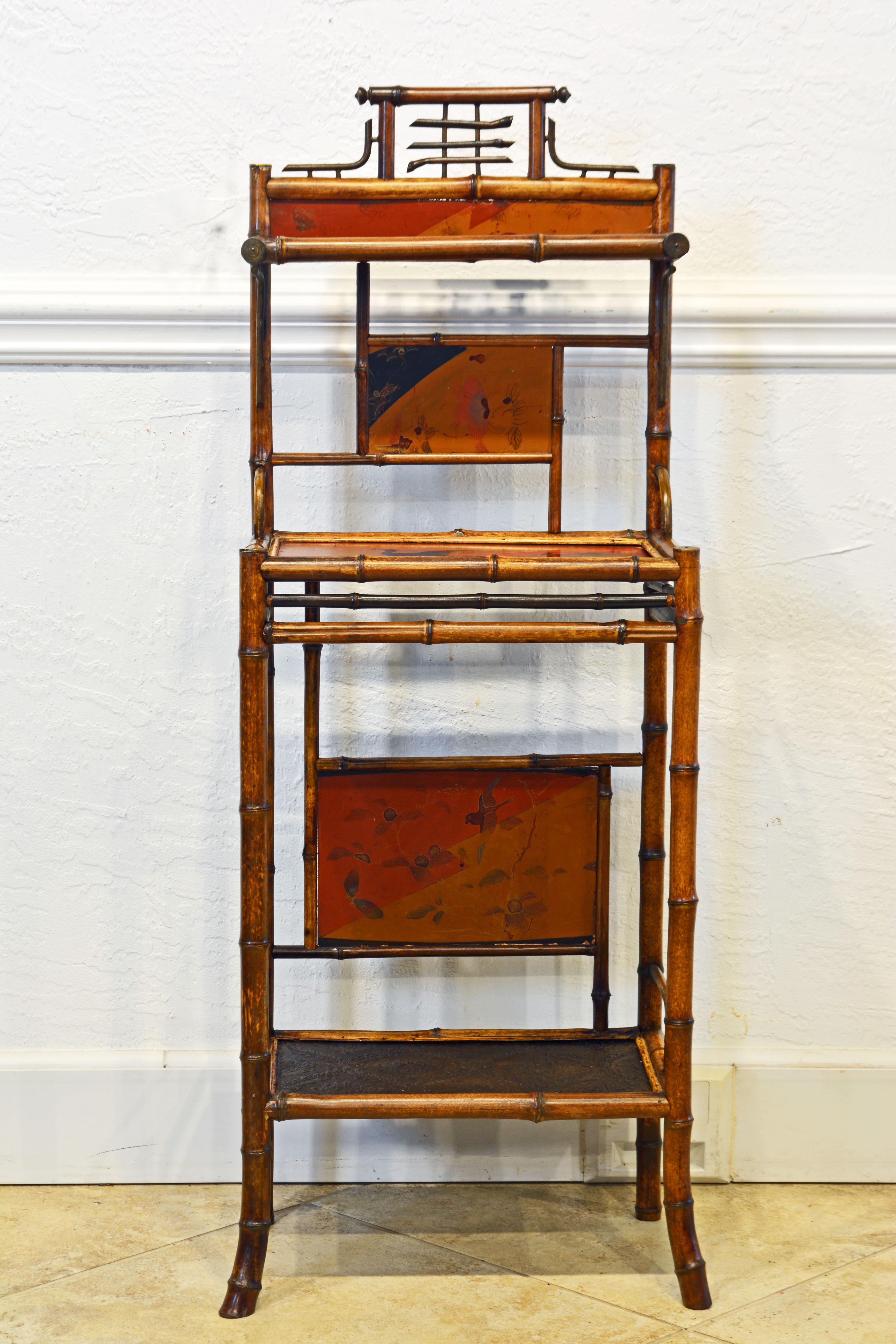 An English Aesthetic Movement chinoiserie style three-tier étagère or stand consisting of a bamboo framework with lacquered and decorated surfaces and panels.