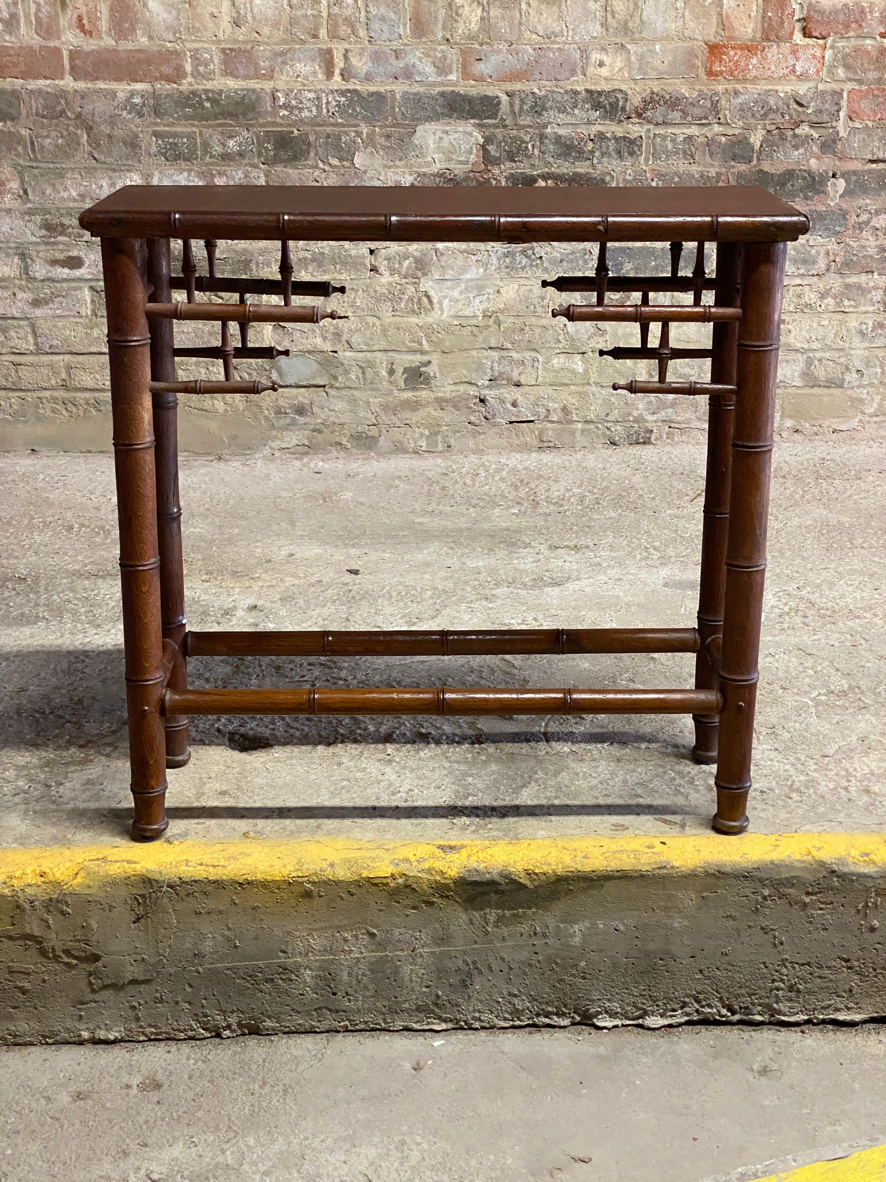 Very good quality Victorian Asian inspired faux bamboo console table. It's very small foot print is a great accent table for a tight area like a hallway or a bathroom. The legs, spindles and top are all oak carved to resemble bamboo. Circa