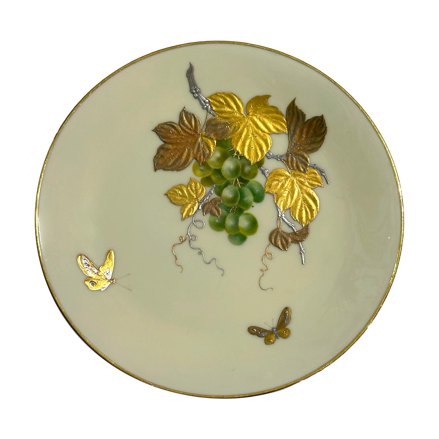 This magnificent porcelain plate signed by Minton, dated 1880, embodies the artistic refinement of the Aesthetic Movement. Finely hand-decorated, it features raised motifs of beautiful grape hanging from a branch elegantly adorned with gold, copper,