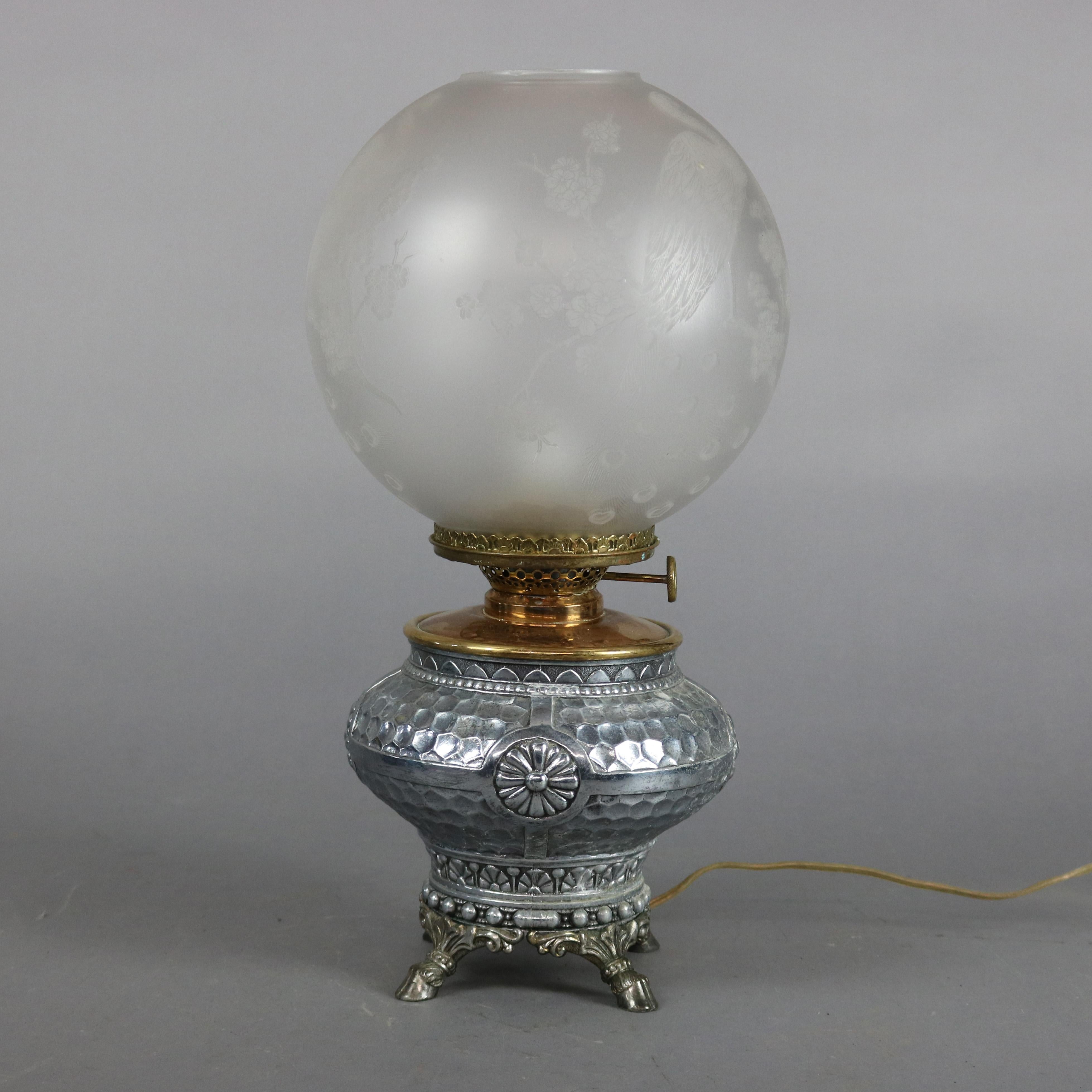 An electrified Aesthetic Movement banquet oil lamp offers etched globe shade with peacock over hammered silver plate base with stylized floral decoration and footed, electrified, circa 1870.

***DELIVERY NOTICE – Due to COVID-19 we are employing