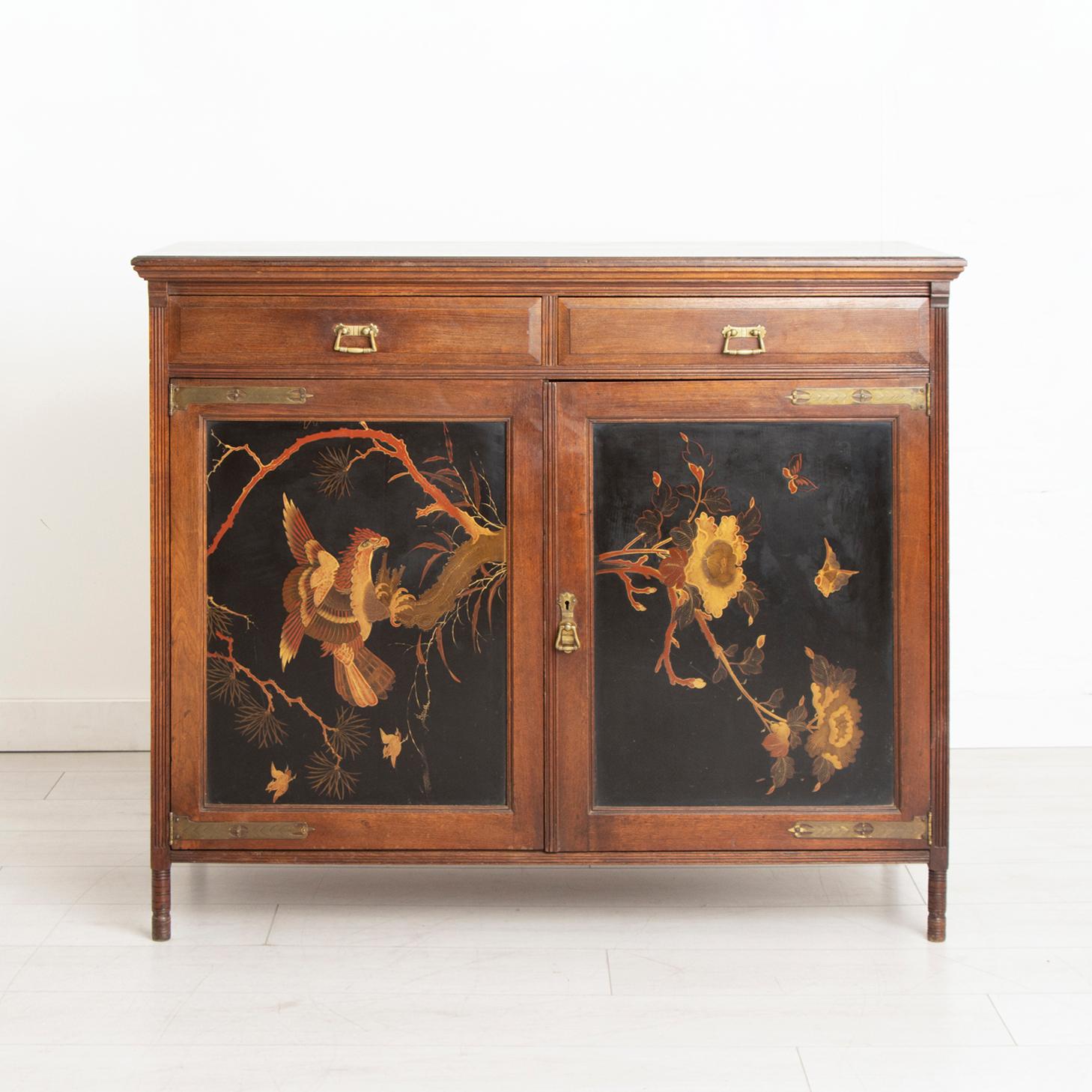 A late 19th-century Aesthetic movement mahogany sideboard with Chinoiserie polychrome lacquered decoration of a bird of prey and blossom tree. The sideboard has a double-doored cupboard with shelving behind and two drawers above.

Dimensions: W