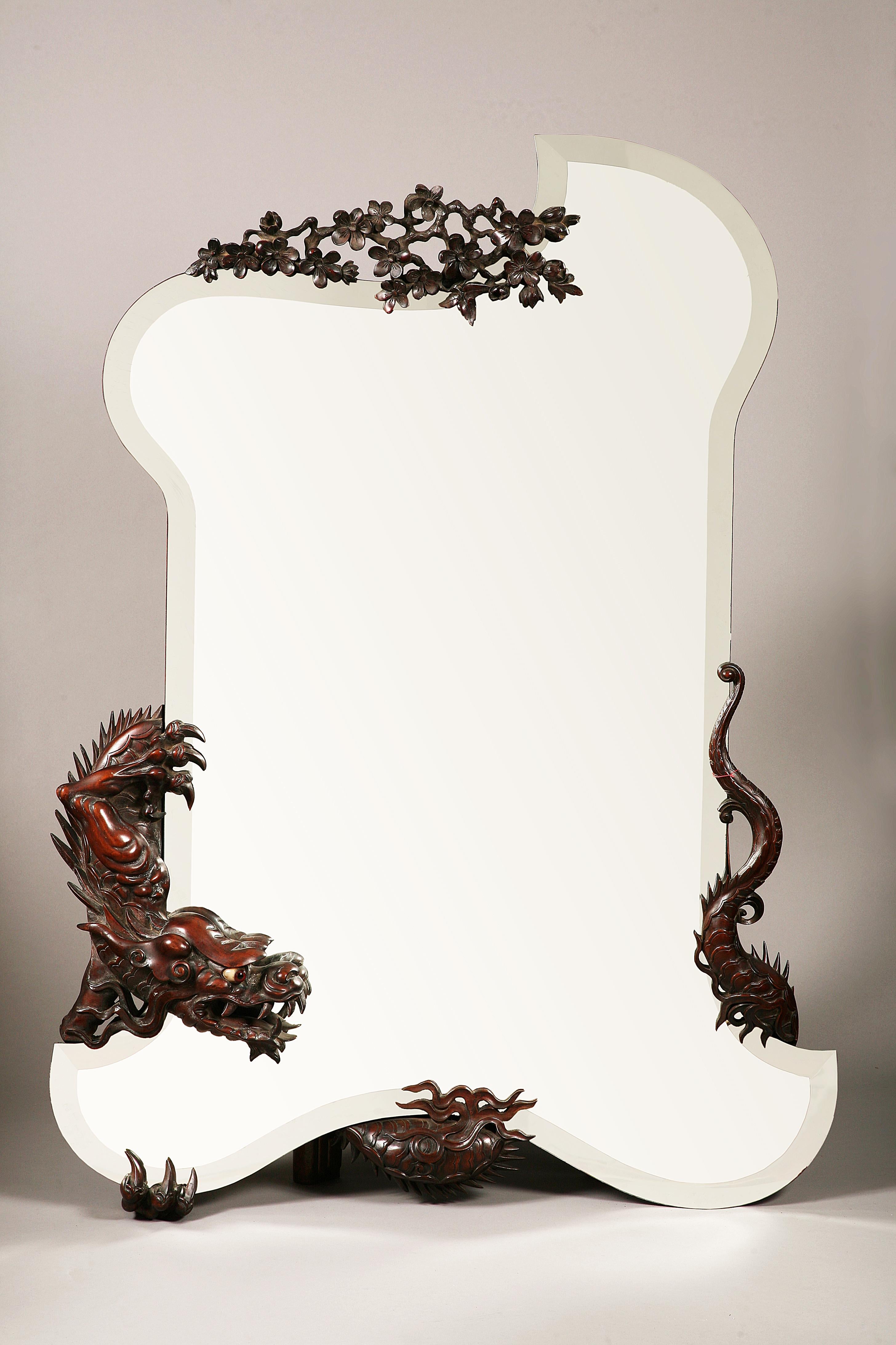 A large Japanese style beveled mirror attributed to G. Viardot, of asymmetrical shape, decorated with a carved tinted wood dragon, wrapped around it. Surmounted by a carved wood Japanese blossoming cherry tree branch.

This mirror is to be linked to