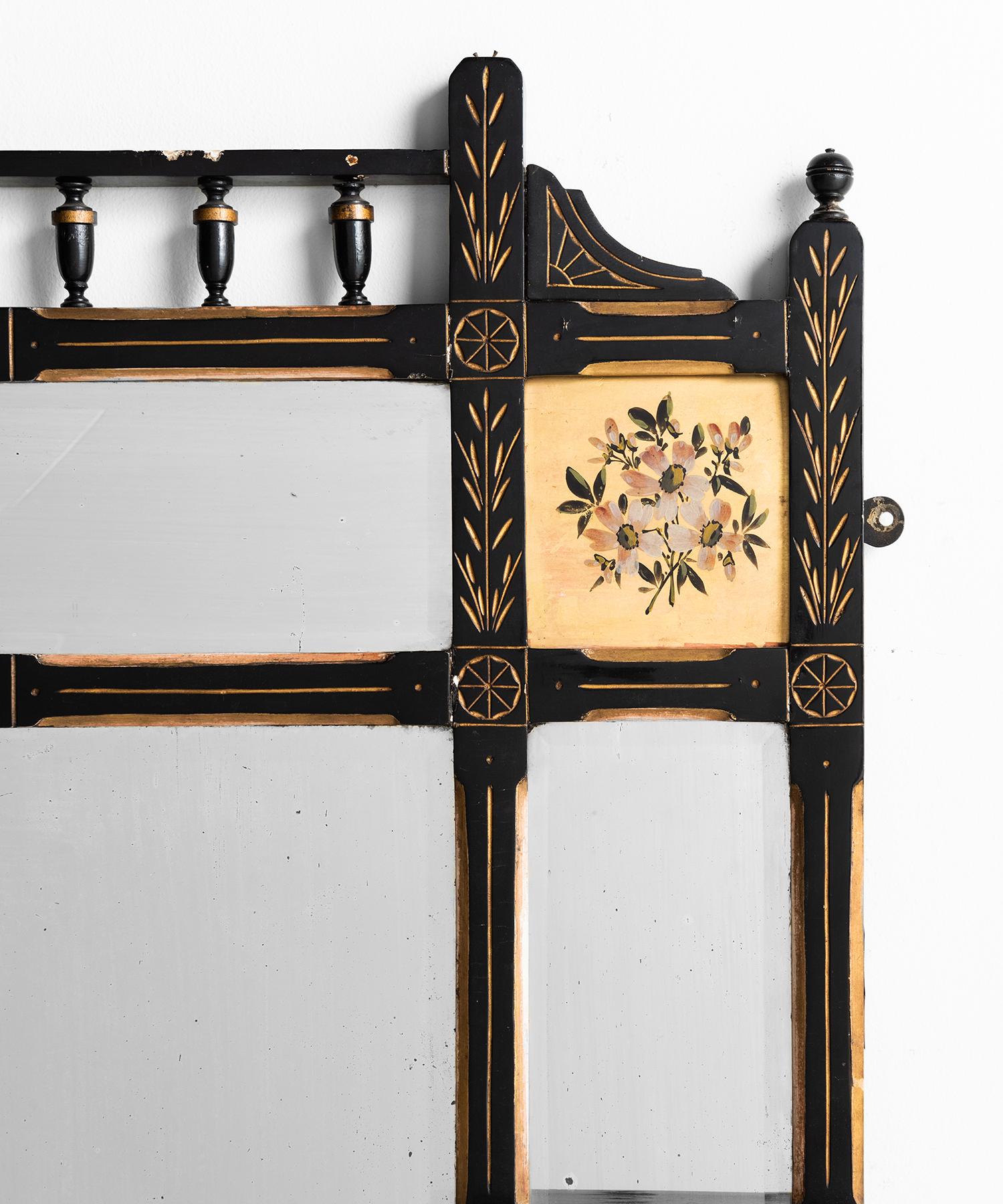 Ebonised finish with gold leaf, decorative inlay and bevelled mirror panels.