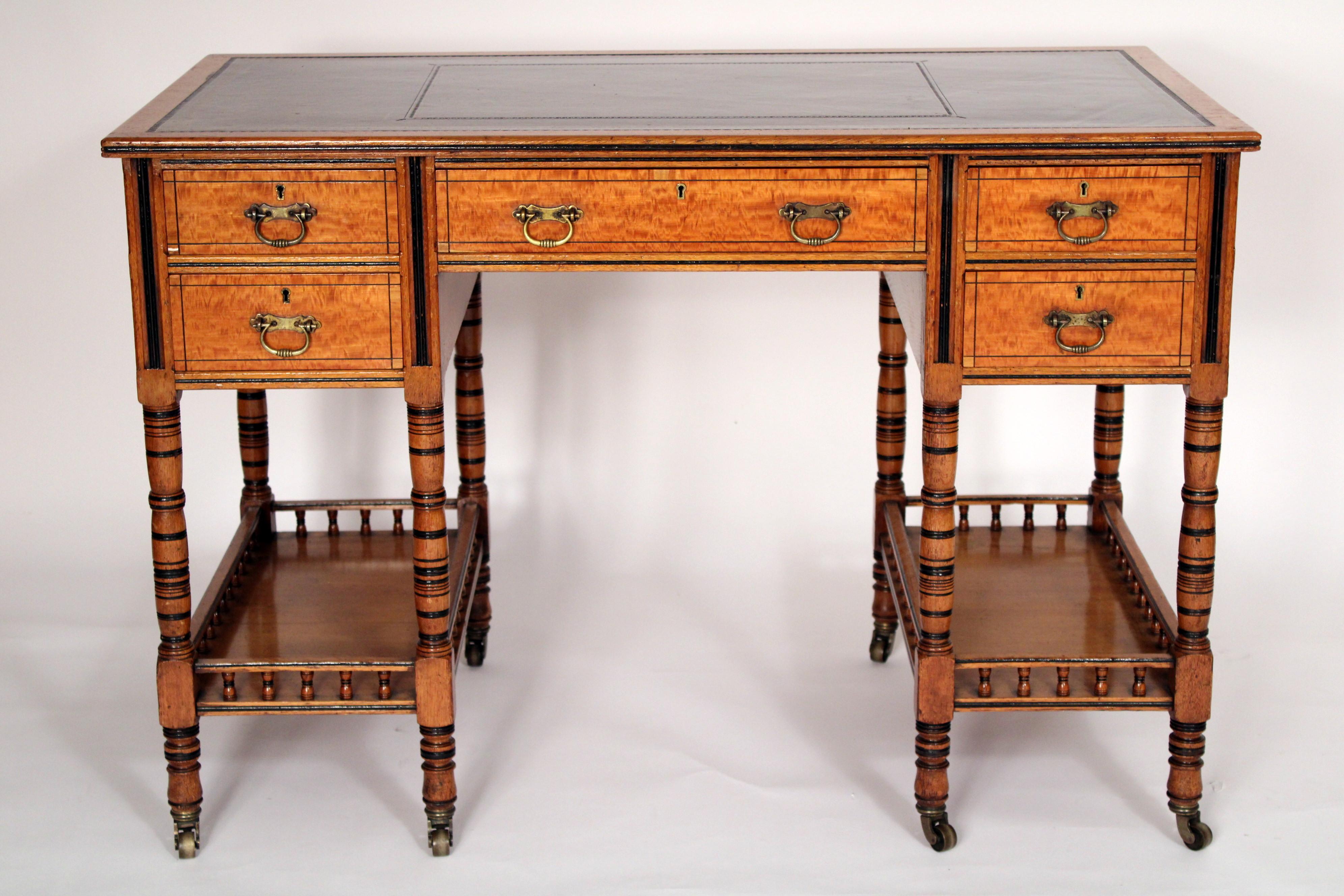 English aesthetic movement satinwood and oak desk with leather top, circa 1900. With a rectangular overhanging oak top inset with tooled leather, central satinwood drawer flanked on either side by two satin wood drawers, satin wood paneled back,
