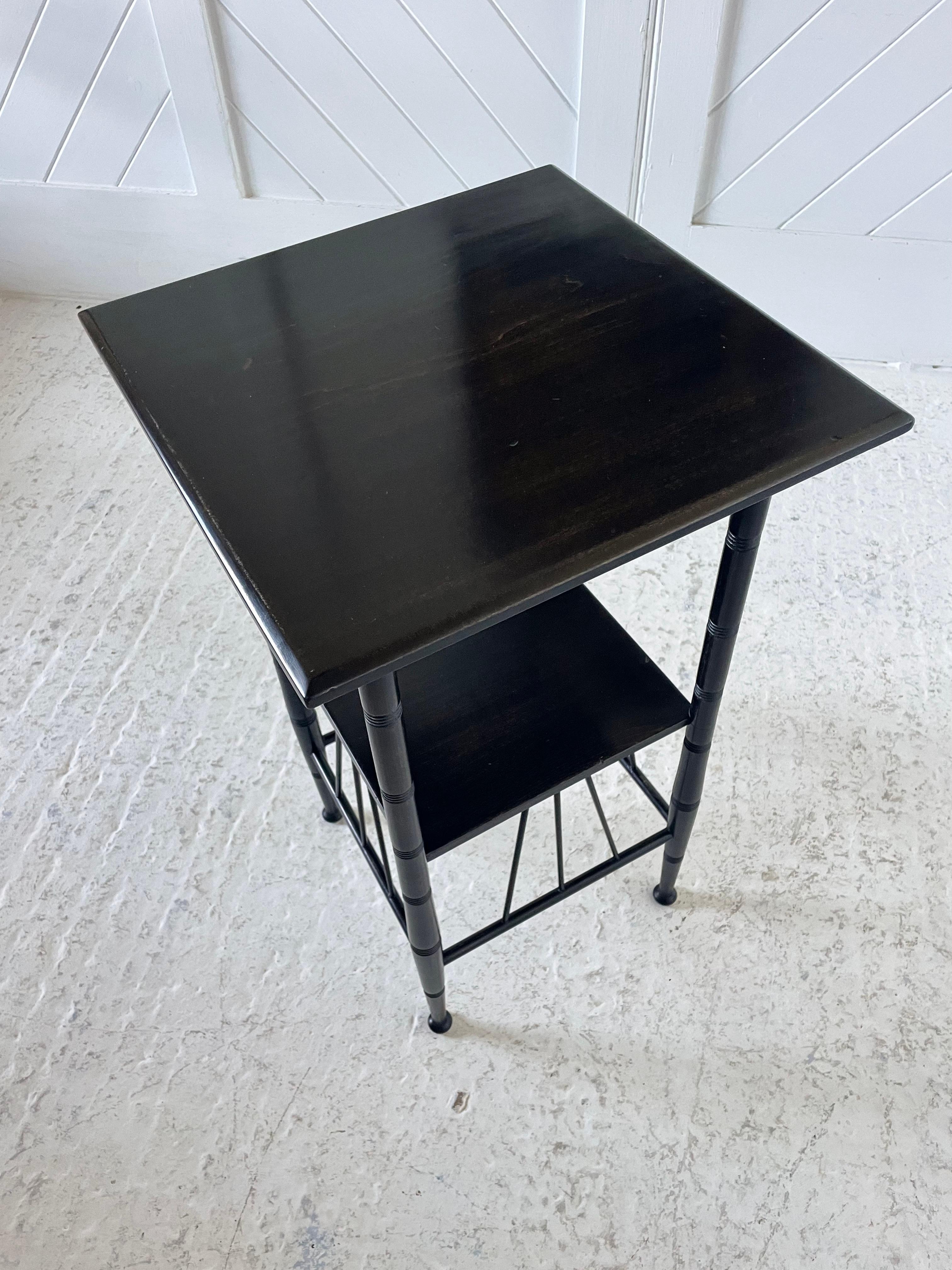 Aesthetic Movement side table in ebonised beech, square top with under tier shelf, turned legs with ring incised detailing with connecting turned and angled struts.

After a design by E.W. Godwin

Circa 1880