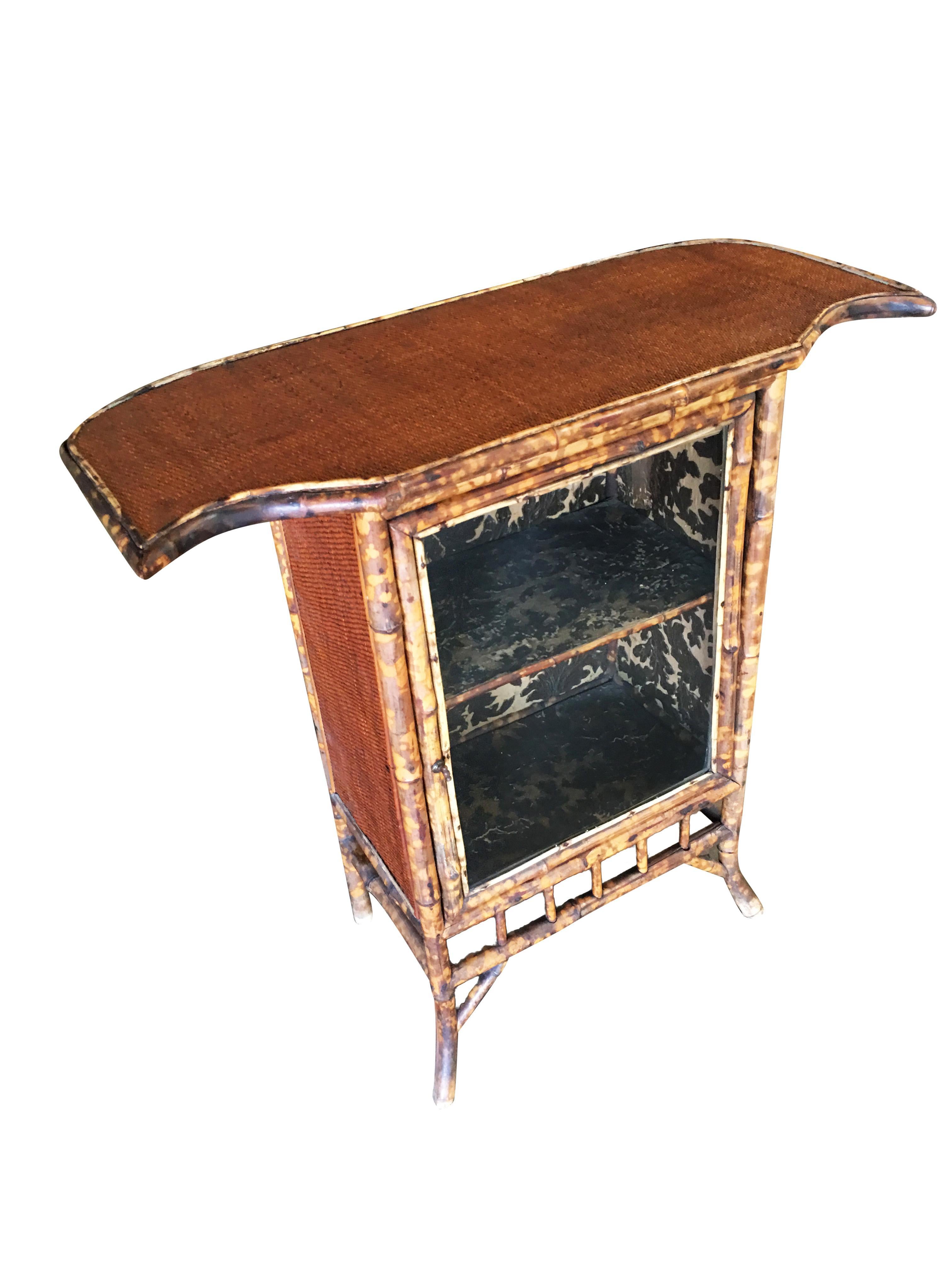 Early 20th century Aesthetic Movement tiger bamboo small 2 person bat wing bar with a unique batwing bar top and small 2 shelf cabinet along the back.
 