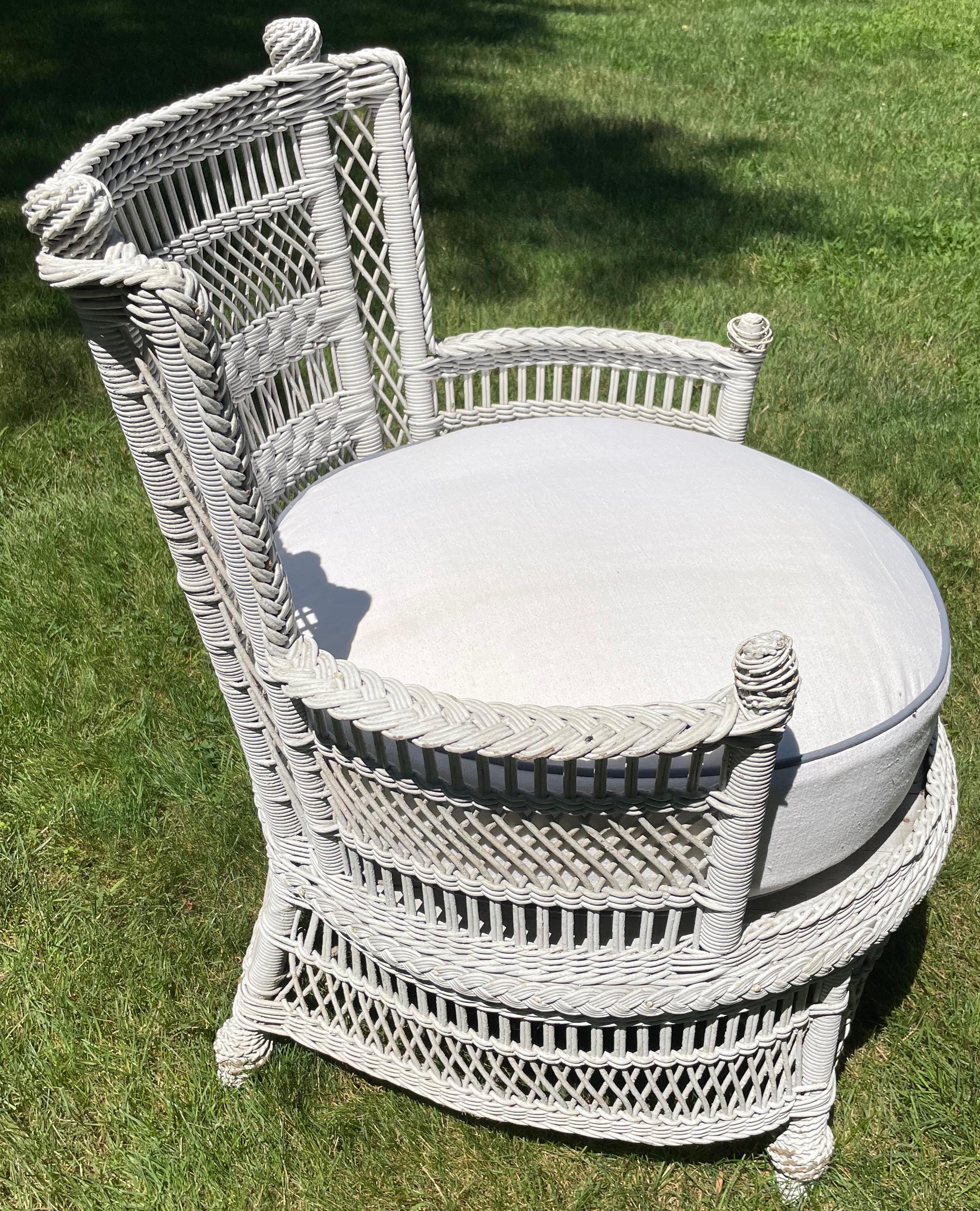 Aesthetic movement white wicker chair. American turn of the century white painted wicker circular arm chair with rounded sides coiled wicker ball finials and thick down and feather Belgian seat cushion in the Aesthetic Movement style. United States,