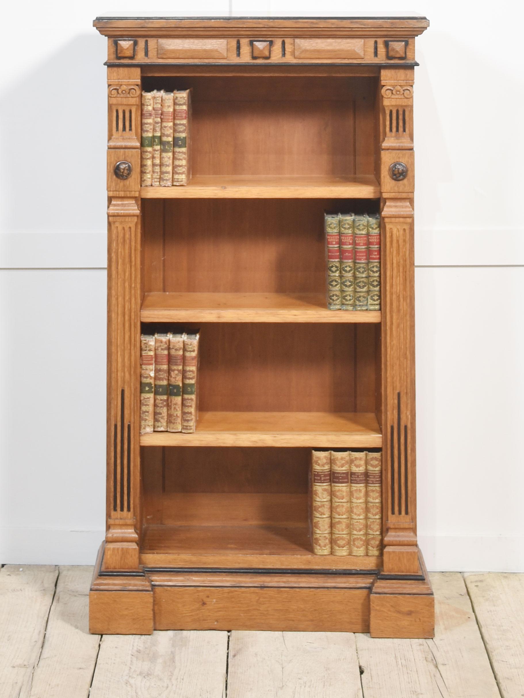 Estetica libreria a giorno in rovere di piccole proporzioni, con piano rettangolare sopra un fregio intagliato con dettagli ebanizzati e scaffali regolabili fiancheggiati da colonne con decorazioni a rilievo. Il tutto sollevato su una base a