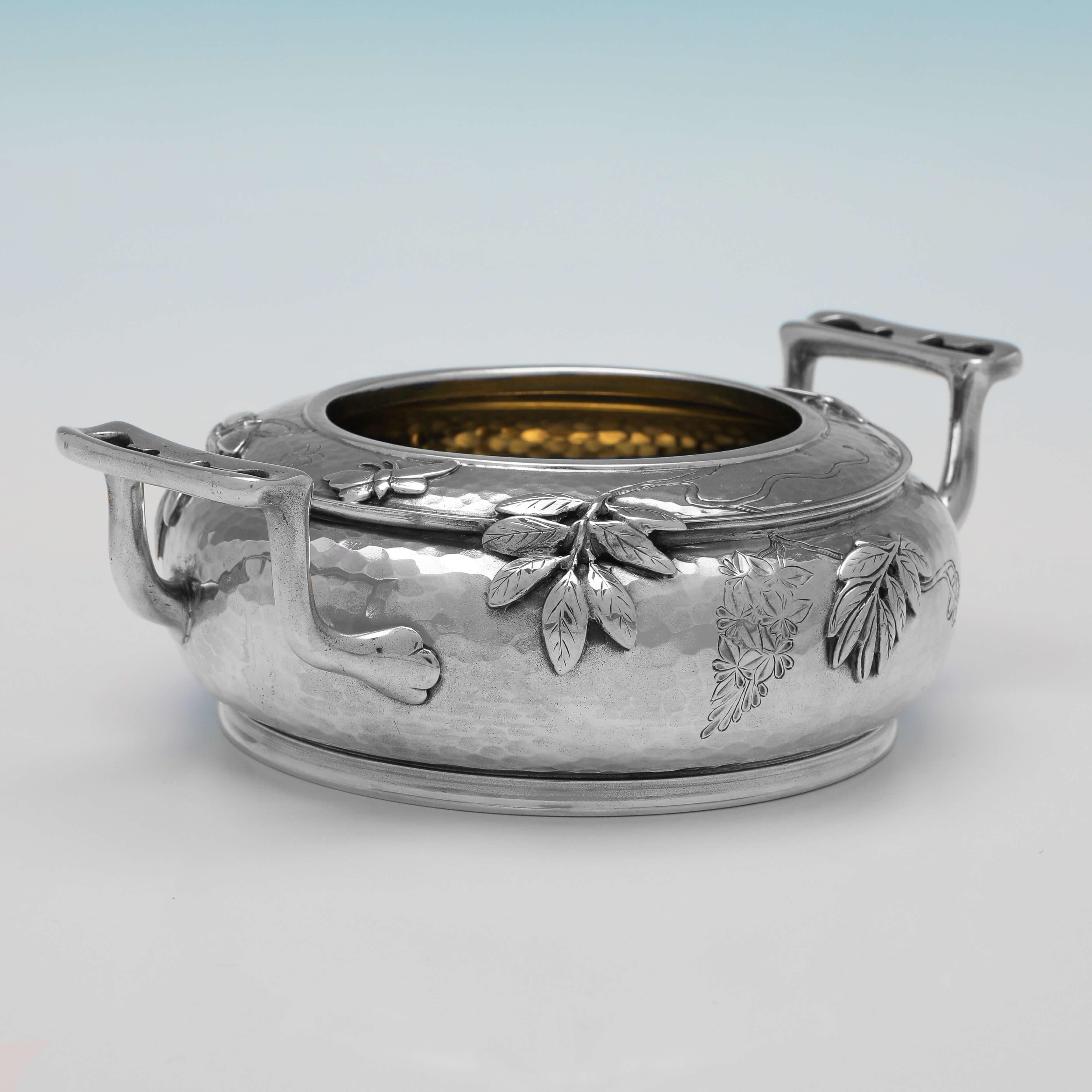 Hallmarked in London in 1879 by Martin, Hall & Co., this stunning, Antique Sterling Silver Bowl, is in the Aesthetic taste, featuring cast and applied floral and butterfly detailing, flat chased decoration, a planished finish, and a gilt interior.