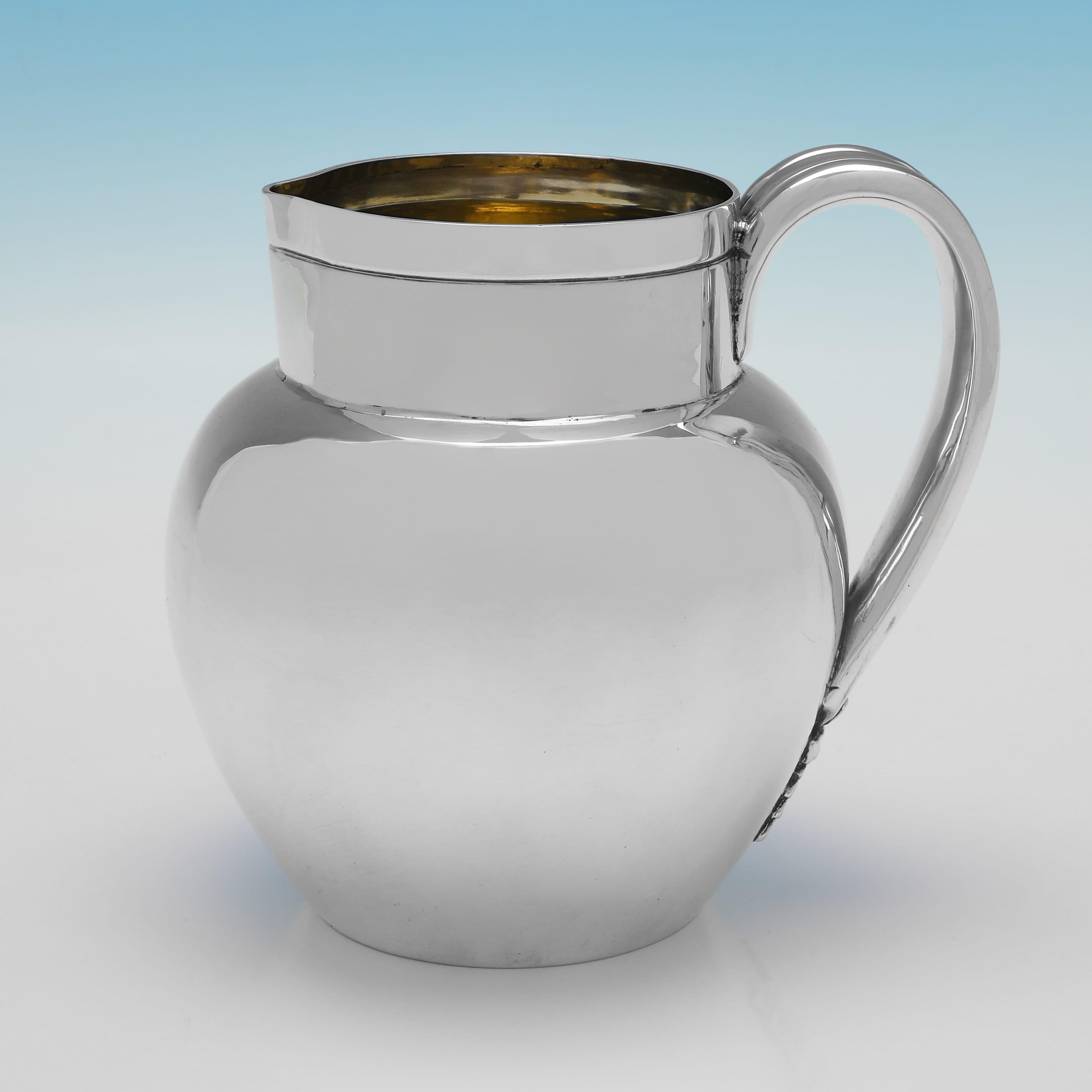 Hallmarked in London in 1889 and 1891 by Aldwinckle & Slater, this handsome, Victorian, Antique Sterling Silver Water Jug and Pair of Beakers, are plain in style, featuring gilt interiors, and floral detailing to the handle of the jug. The water jug
