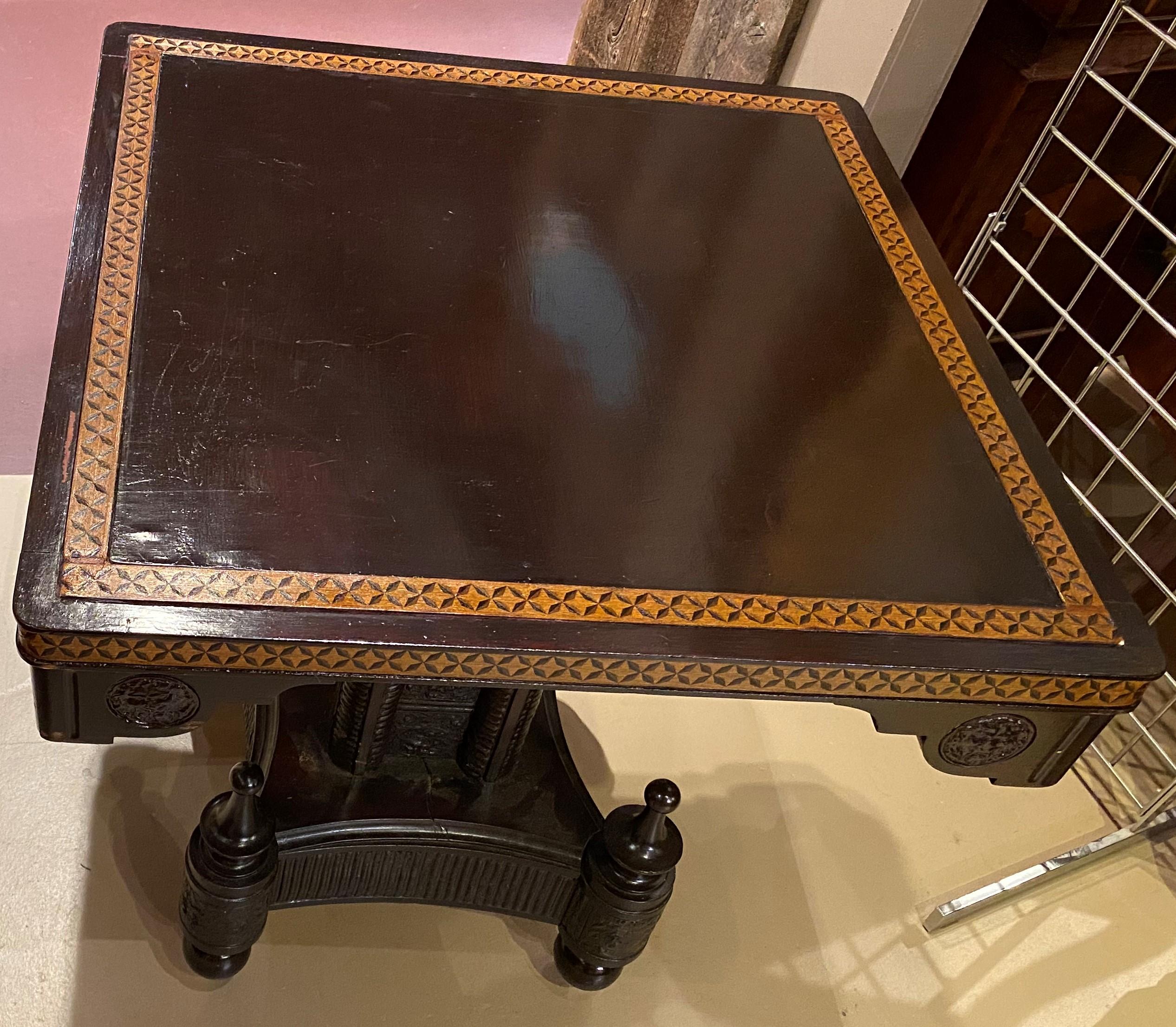 Un bel tavolo da centro quadrato con piano inclinabile del periodo estetico nella sua finitura scura originale, con piano con bordo intarsiato, decorazioni angolari intagliate, sostenuto da un piedistallo rivestito in pelle modellata e una base