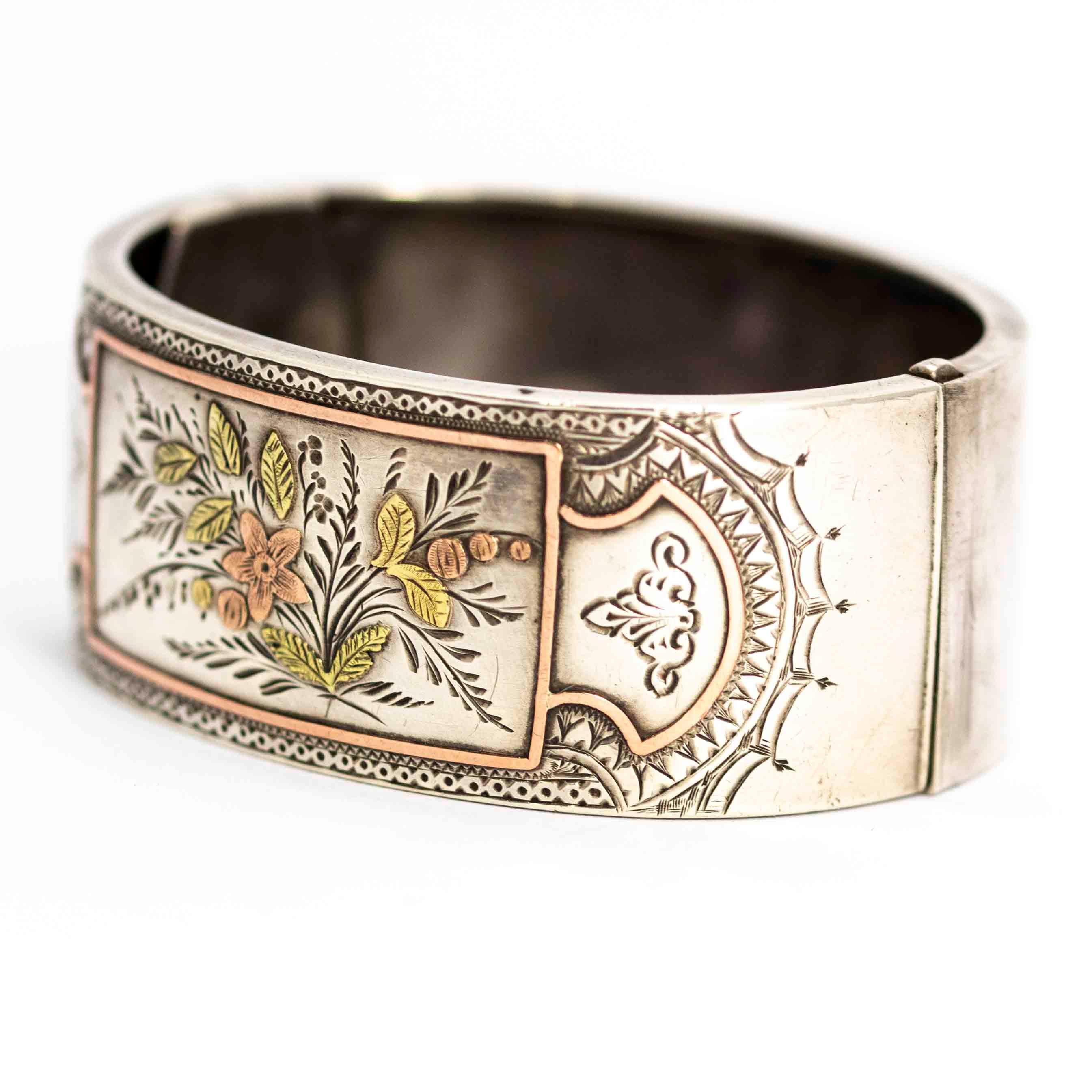 An exquisite antique bangle from the aesthetic movement in the Victorian era circa 1870. Decorated with superb hand-chased detailing with rose gold and yellow gold overlay leaf and flower motifs. Modelled in silver.

Width: 6.3cm (from hinge to
