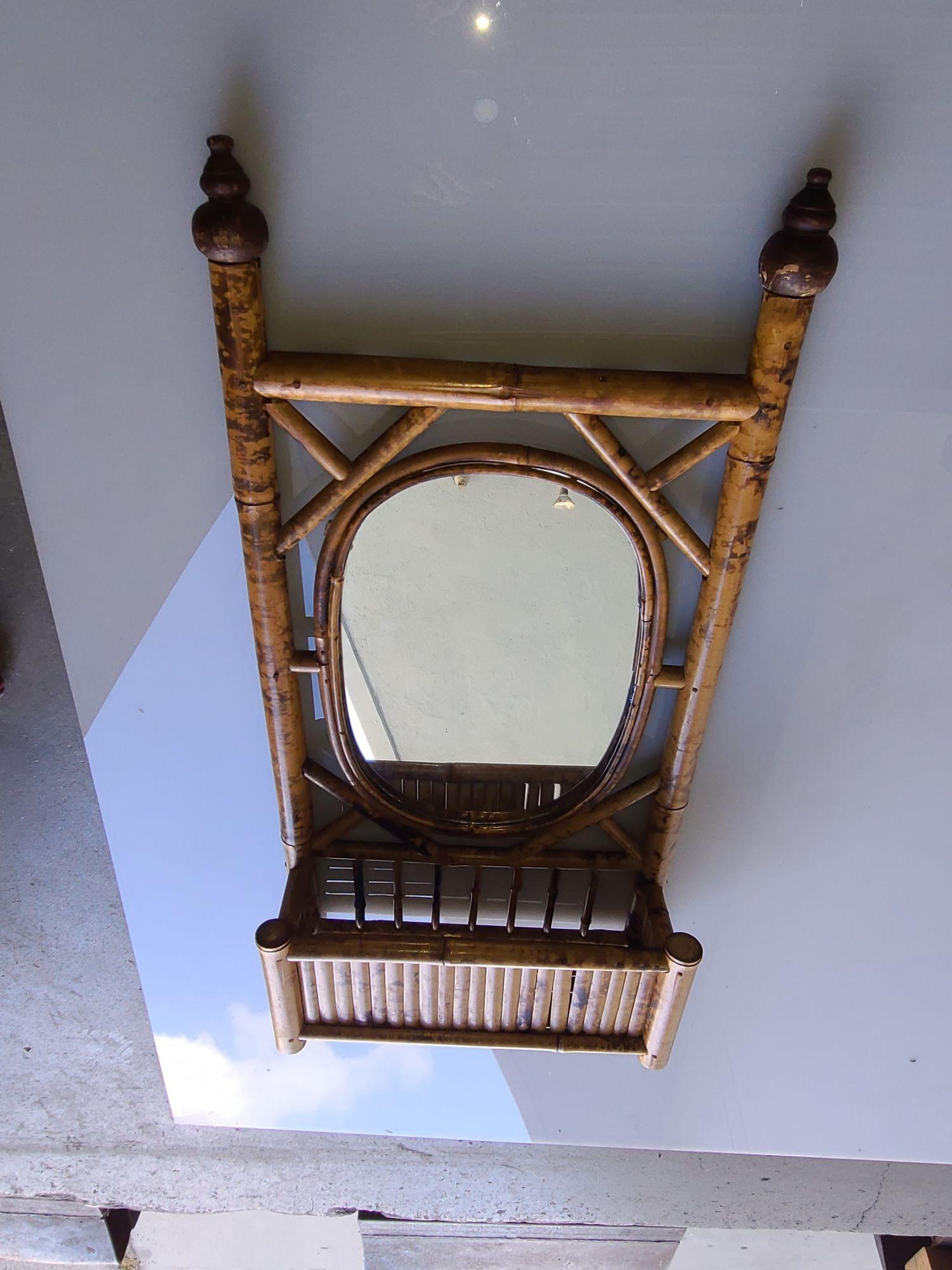 Antique 1900 Aesthetical Movement tiger bamboo wall mirror with holder. The mirror features an oval-shaped frame fixed to a frame that ends at two pinnacles. Along the bottom is a small holder for personal effects.

Mirror Dimensions: 13