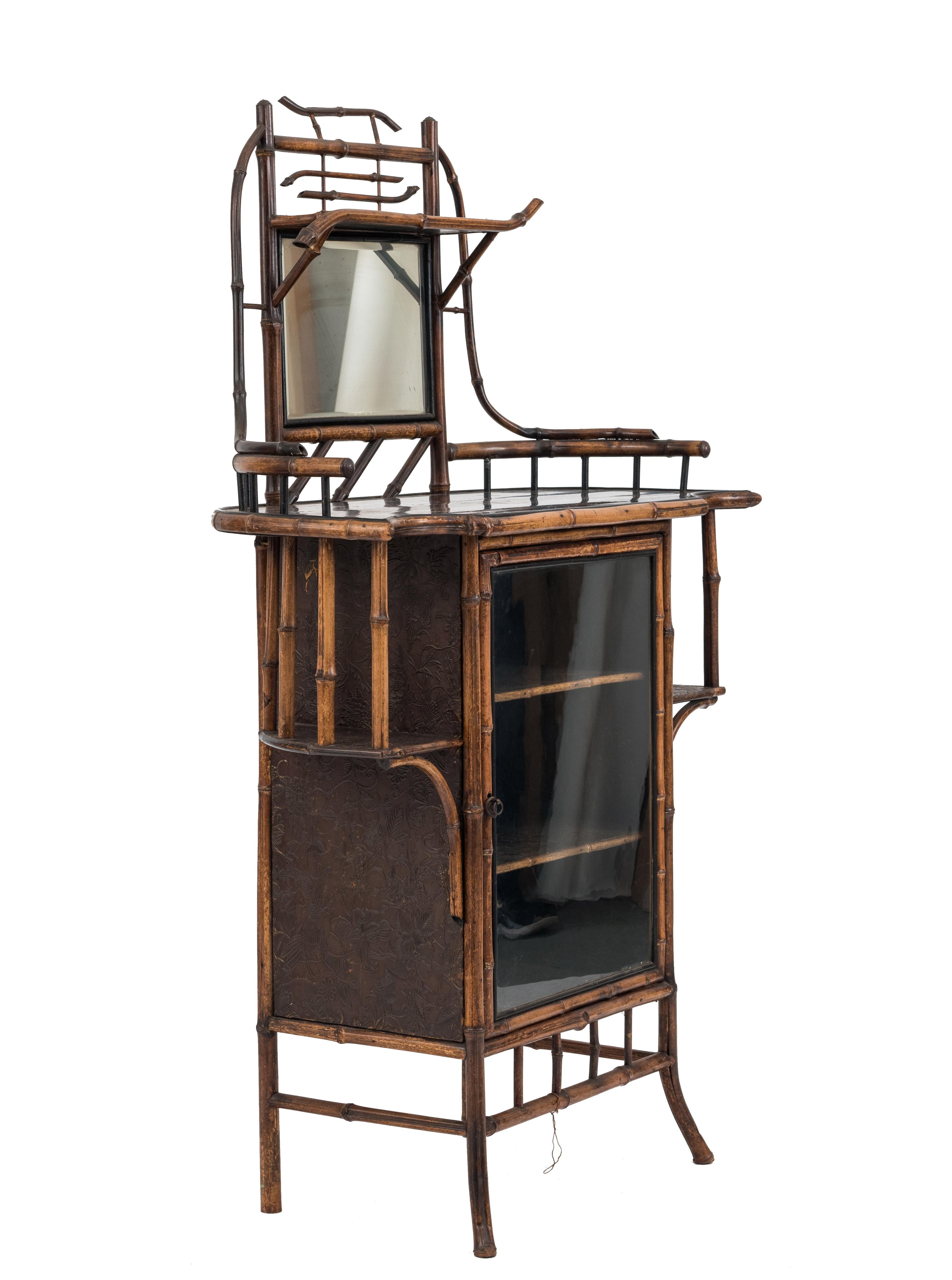 Late 19th-early 20th century bamboo étagère with side shelves, glass door, and mirrored upper section with shaped black lacquered decorated top.