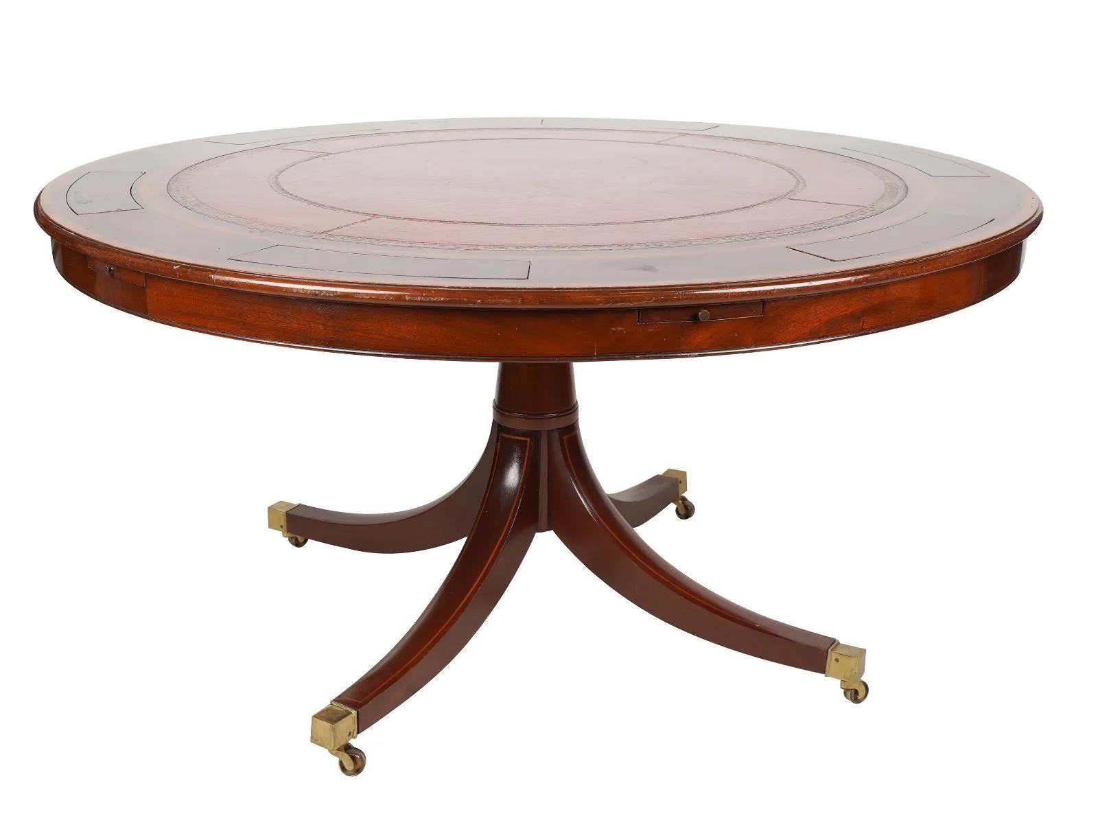 Late 20th Century English Regency Mahogany Poker Table with a gilt tooled burgundy leather inset top; 6 sliding drink holders and 6 game piece compartments; rising on 4 out swept legs terminating with brass casters. 

Provenance: Purchased from the
