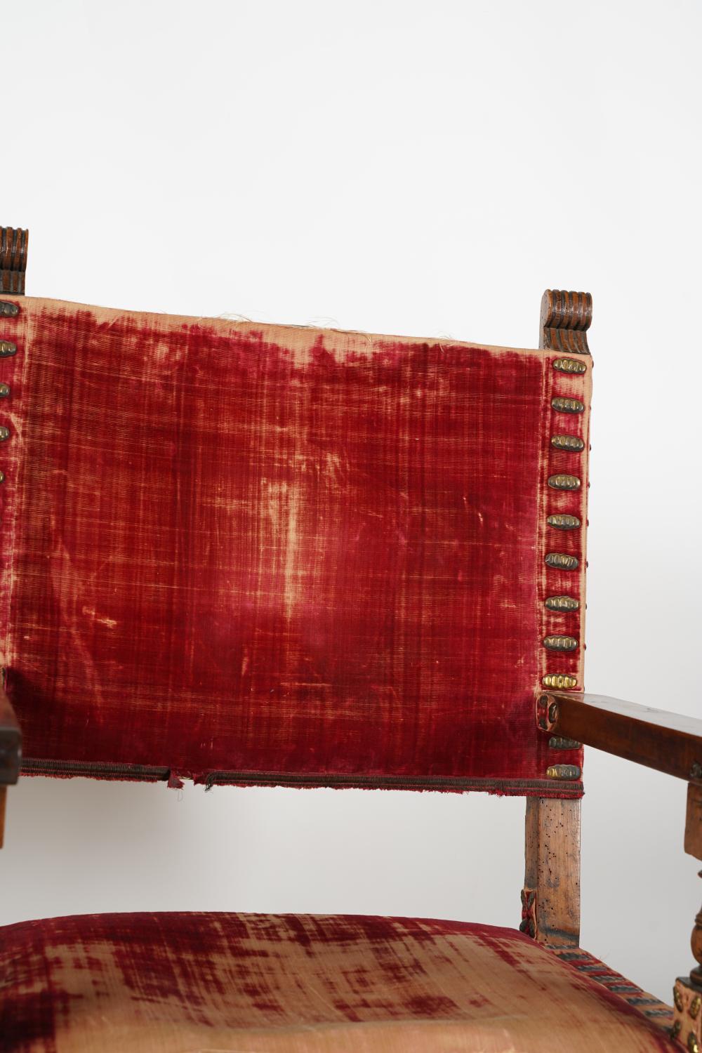 Ancienne paire de chaises à accoudoirs en noyer sculpté de style baroque espagnol de la fin du XVIIIe siècle, avec clous décoratifs en laiton sur velours rouge usé. Magnifique bois de noyer patiné et vieilli. Barres d'appui sculptées et percées de