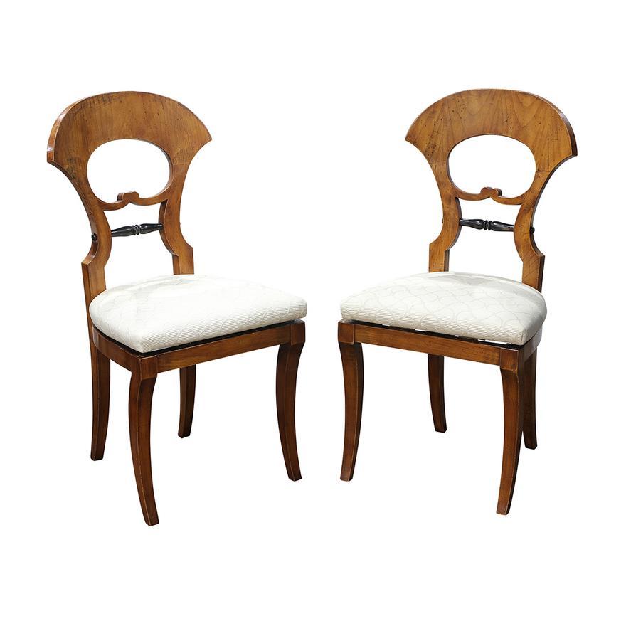 Ensemble de 7 chaises de salle à manger Biedermeier autrichiennes datant de 1820, exécutées en bouleau, avec une crête courbée se poursuivant jusqu'au support du dossier ébonisé et tourné, et reposant sur des pieds inclinés vers l'extérieur. 