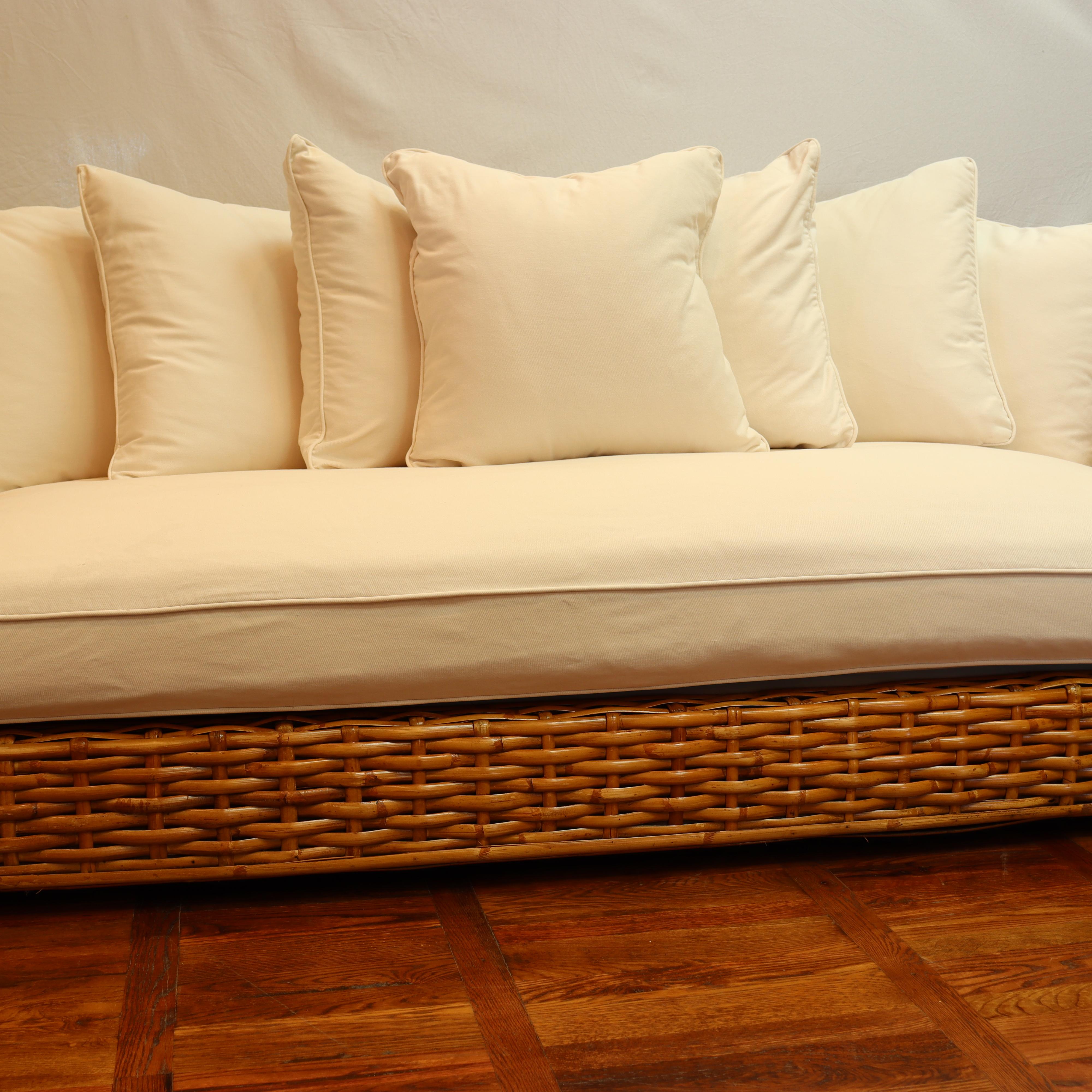 Quality Made Circa 2007 Restoration Hardware woven rattan sofa with down filled white cotton upholstered cushions. Seat cushion constructed with a down envelope surrounding a foam core. Back cushions are all down filled. Both the woven rattan frame