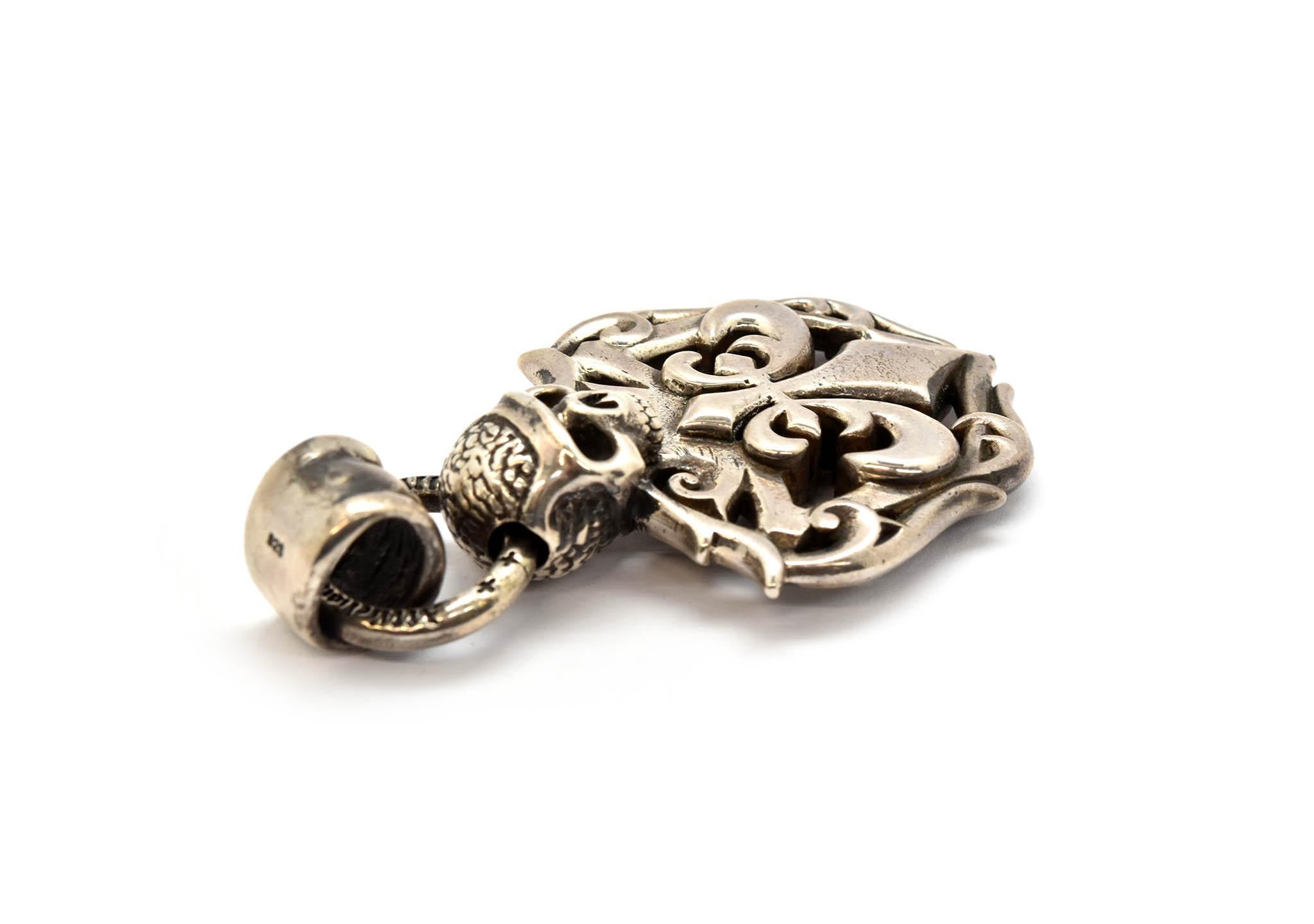This pendant is made in sterling silver by Affliction. The pendant features a fleur de lis with a skull on top. The pendant measures 73x40mm, and it weighs 72.5 grams. The pendant is signed 