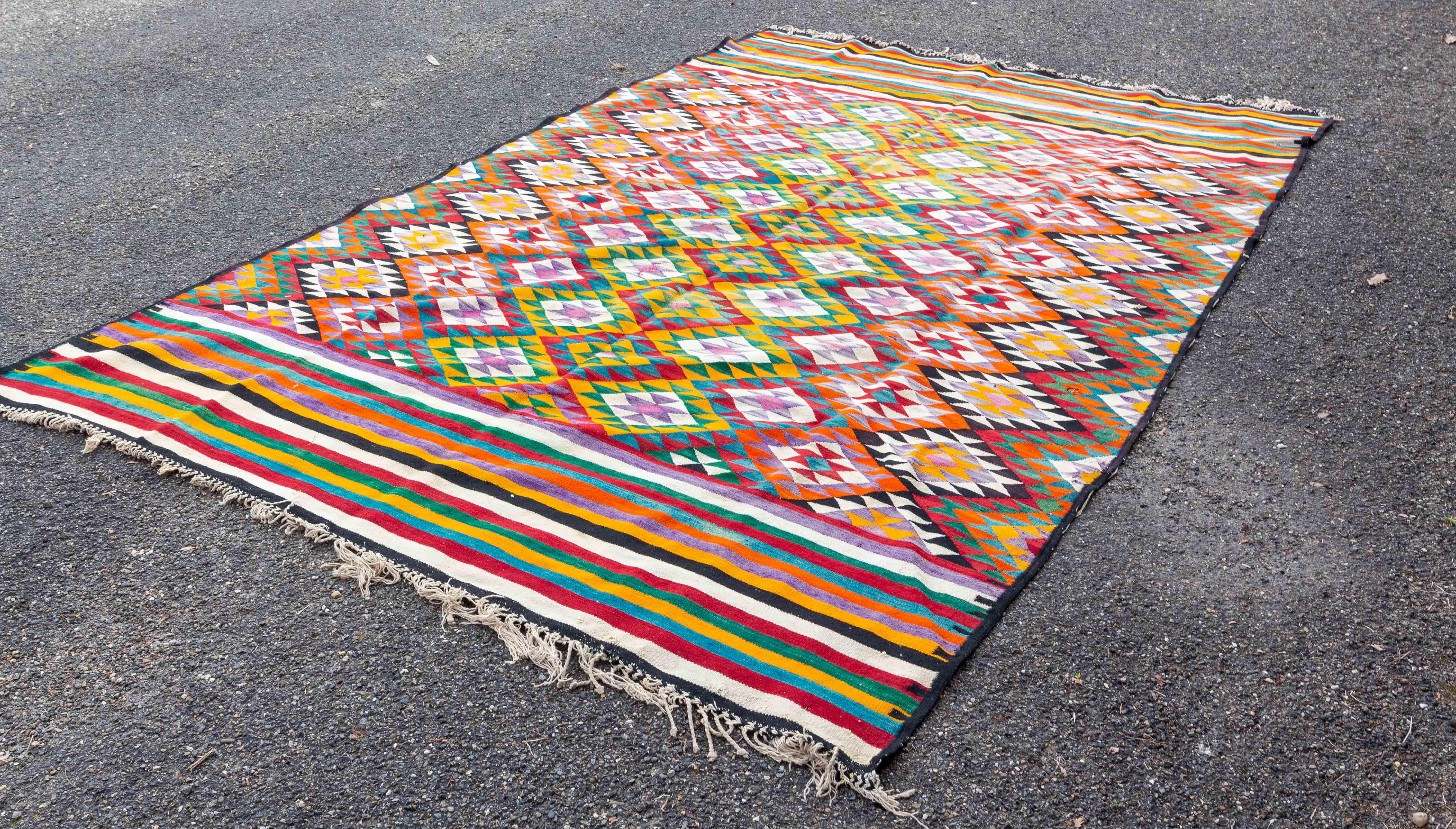 Hand woven in wool and native to Turkey around 1950-1960, this article is a vintage Kilim rug that evokes a Turkish diamond motif from the middle of the last century, appeared at that time, known for producing Kilim rugs with modern and maximalist