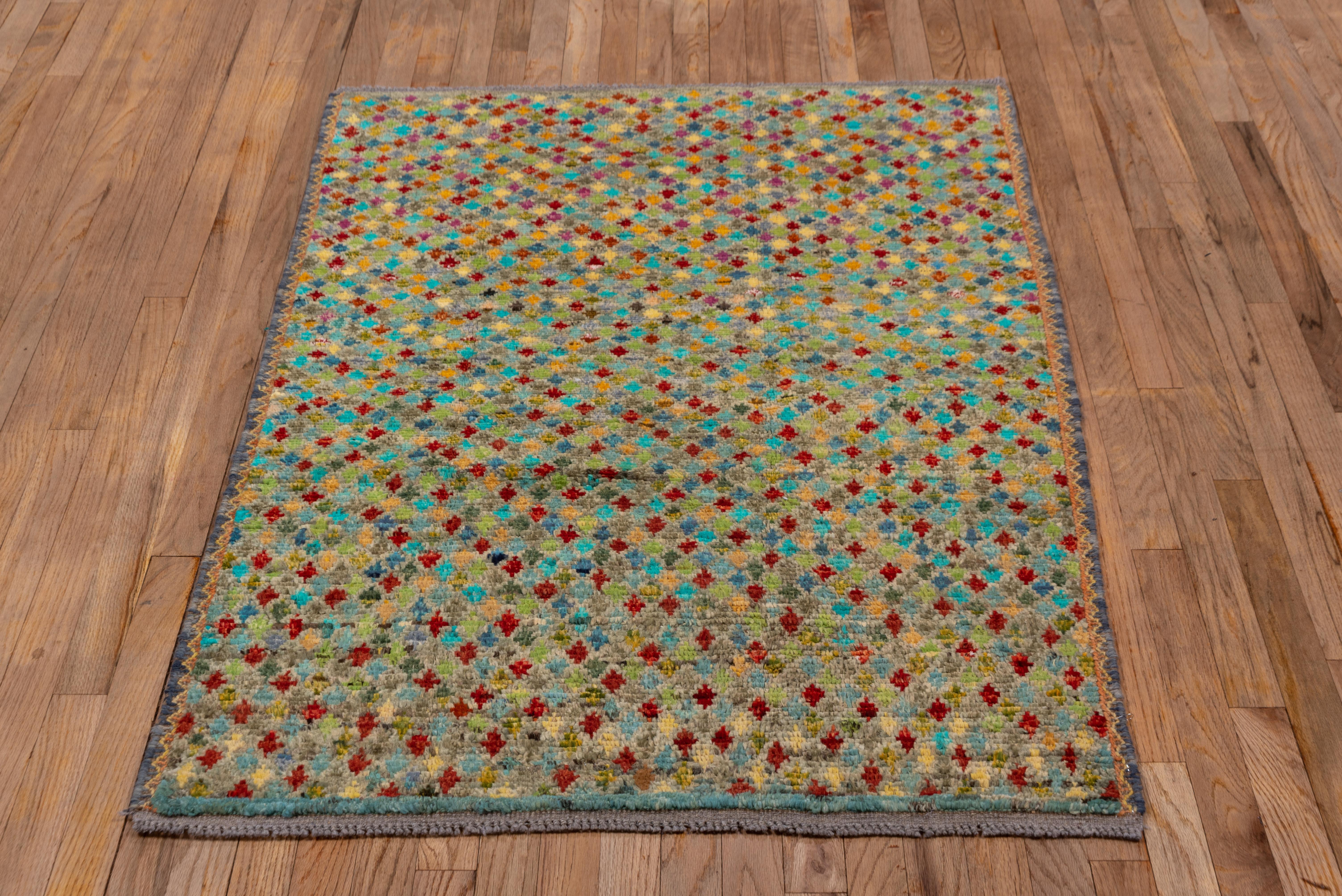This rug has tiny lozenges in a random arrangement of colors including red, goldenrod, straw, teal, sky blue and celadon densely cover the ground of this small as new scatter with narrow, zig-zag side borders. Every color section is abrashed,