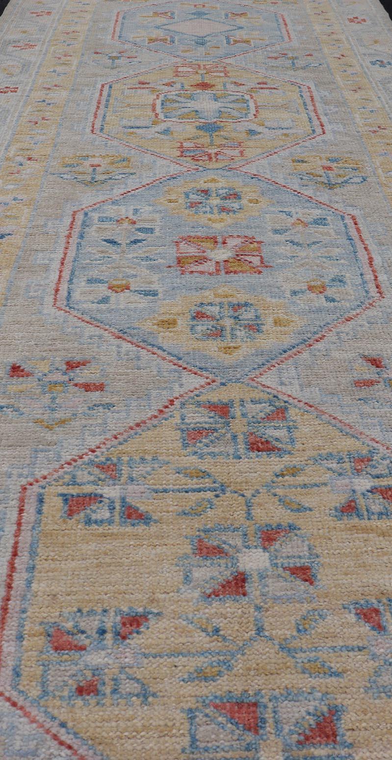 This piece showcases brilliant medallions encasing star-like motifs in yellow, coral, orange, light blue, and cream. The border displays a  yellow band between a cream background.

Measures; 2'9 x 7'11 

Keivan Woven Arts; rug AWR-6116 Country of