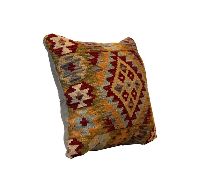 This handwoven wool Kilim cushion cover was constructed in Afghanistan in the late 20th/ early 21st century. This fantastic cushion features a geometric diamond pattern woven in beige, orange, brown, green, and grey accents. Both the colour palette