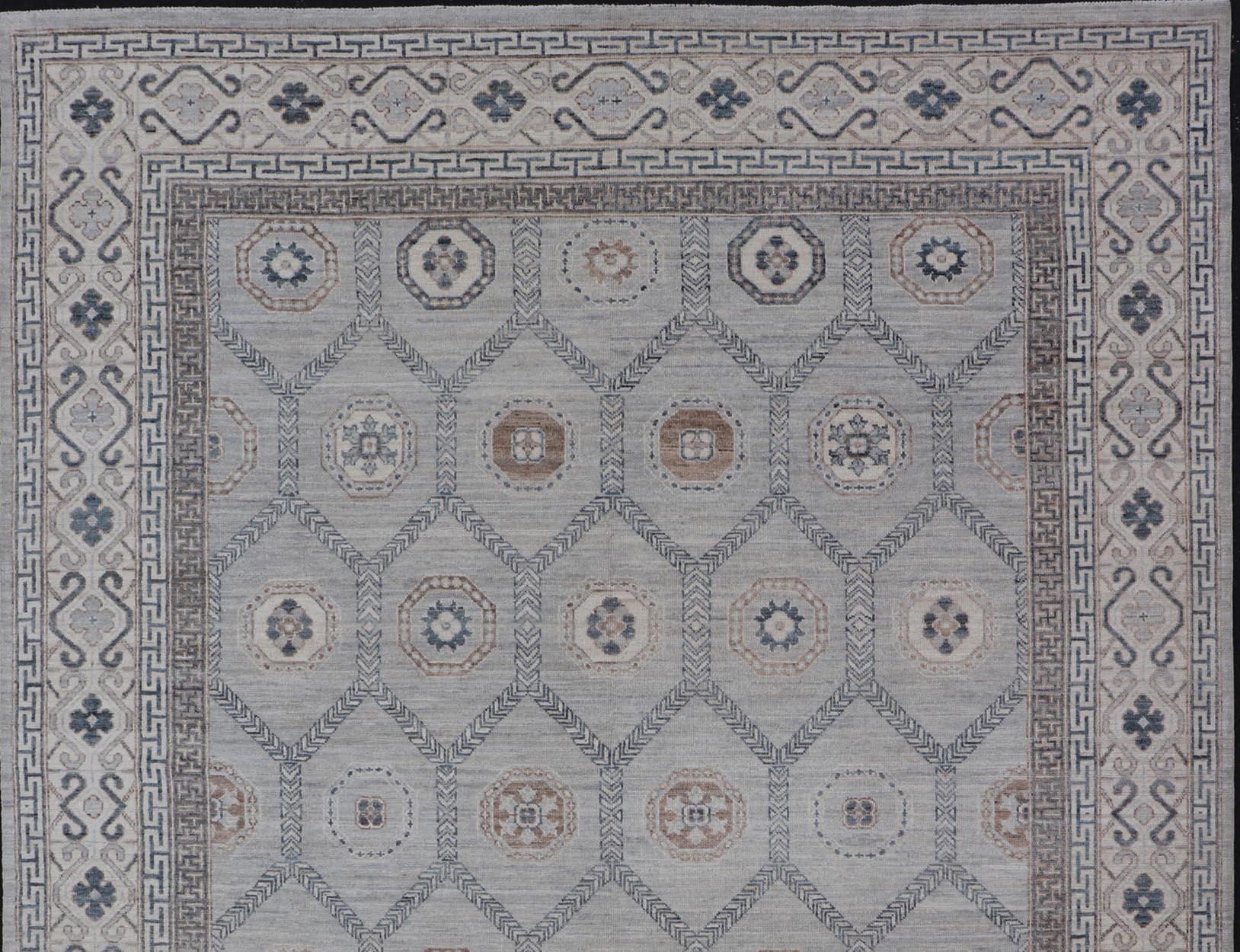 This hand-knotted Khotan features geometric medallions, each of which hold a small geometric motif. The border hosts different geometric designs on each tier, alternating between an ivory and dark teal green motifs on a cream background.
Measures;