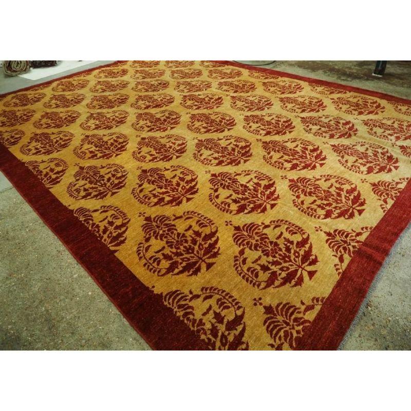 The carpet has an all over large scale design in a burgundy red on a yellow / gold field, framed by a plain burgundy red border; this gives the rug a classic yet contemporary feel. The repeat design to the field is a large flowering tree or