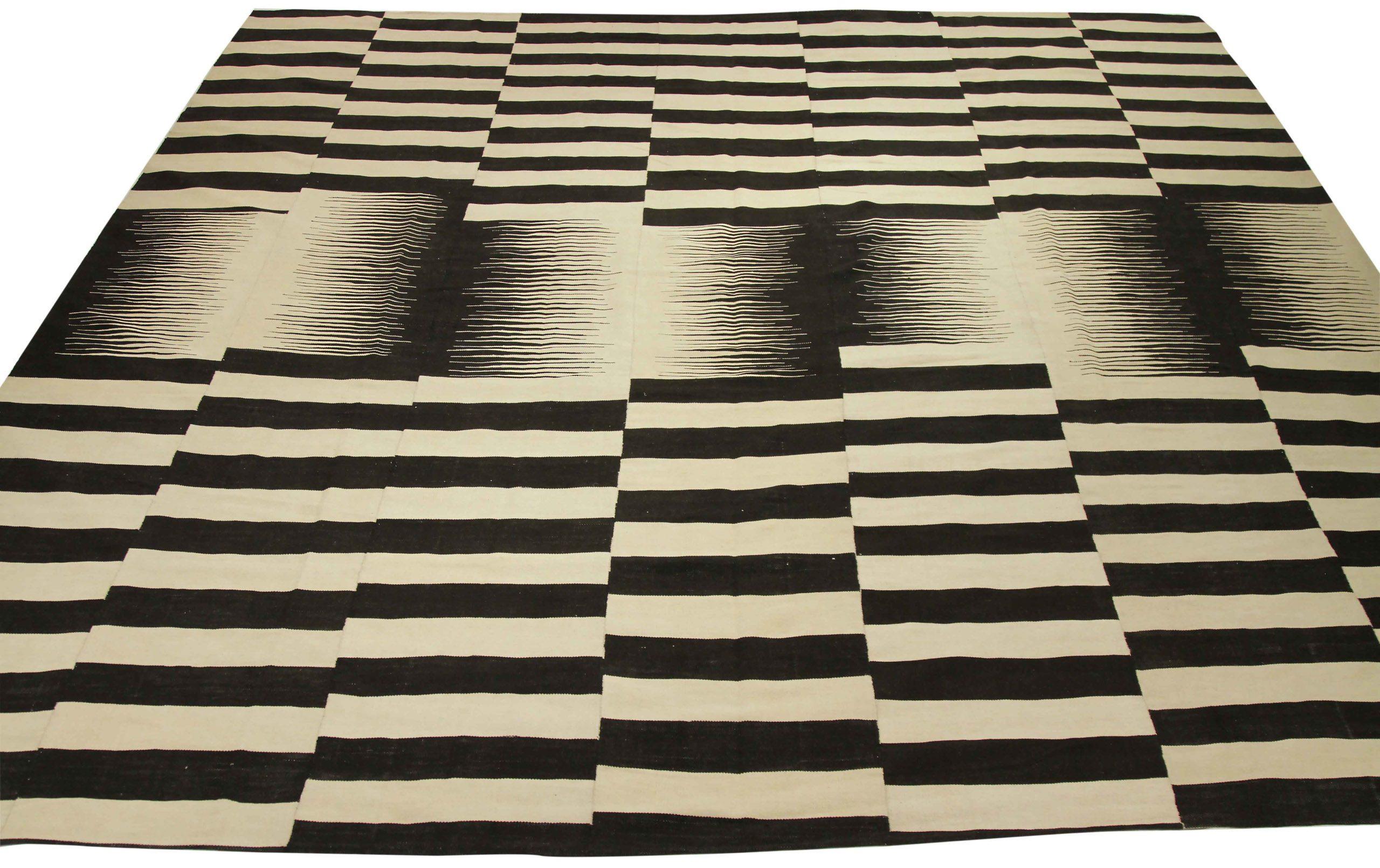 Entdecken Sie die Eleganz eines afghanischen Kilims mit einem übergroßen Teppich aus der Zeit um 1990. Dieses exklusive Design aus Wolle und Schwarz-Elfenbein eignet sich perfekt, um Ihren Raum aufzuwerten.