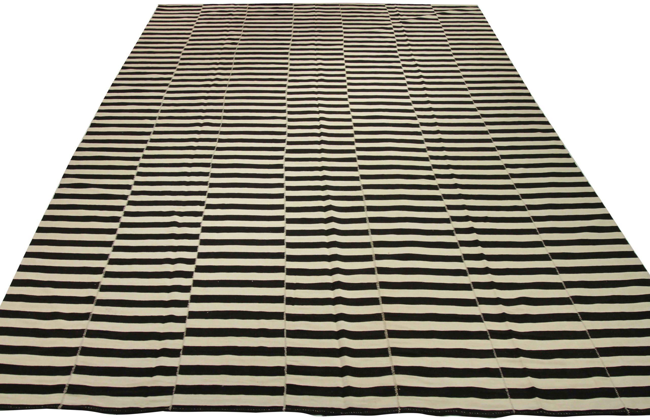 Scopri l'eleganza del Rug & Kilim dell'Afghanistan, caratterizzato da un tappeto over size del 1990. Progettato in lana e nero-avorio, questo design esclusivo è perfetto per valorizzare il tuo spazio.