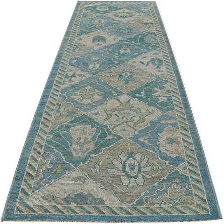 Scopri l'eleganza della collezione Afghanistan Rose con il tappeto Runner di CIRCA 1990. Progettato con lana e blu-verde-avorio, questo design esclusivo è perfetto per valorizzare il tuo spazio.