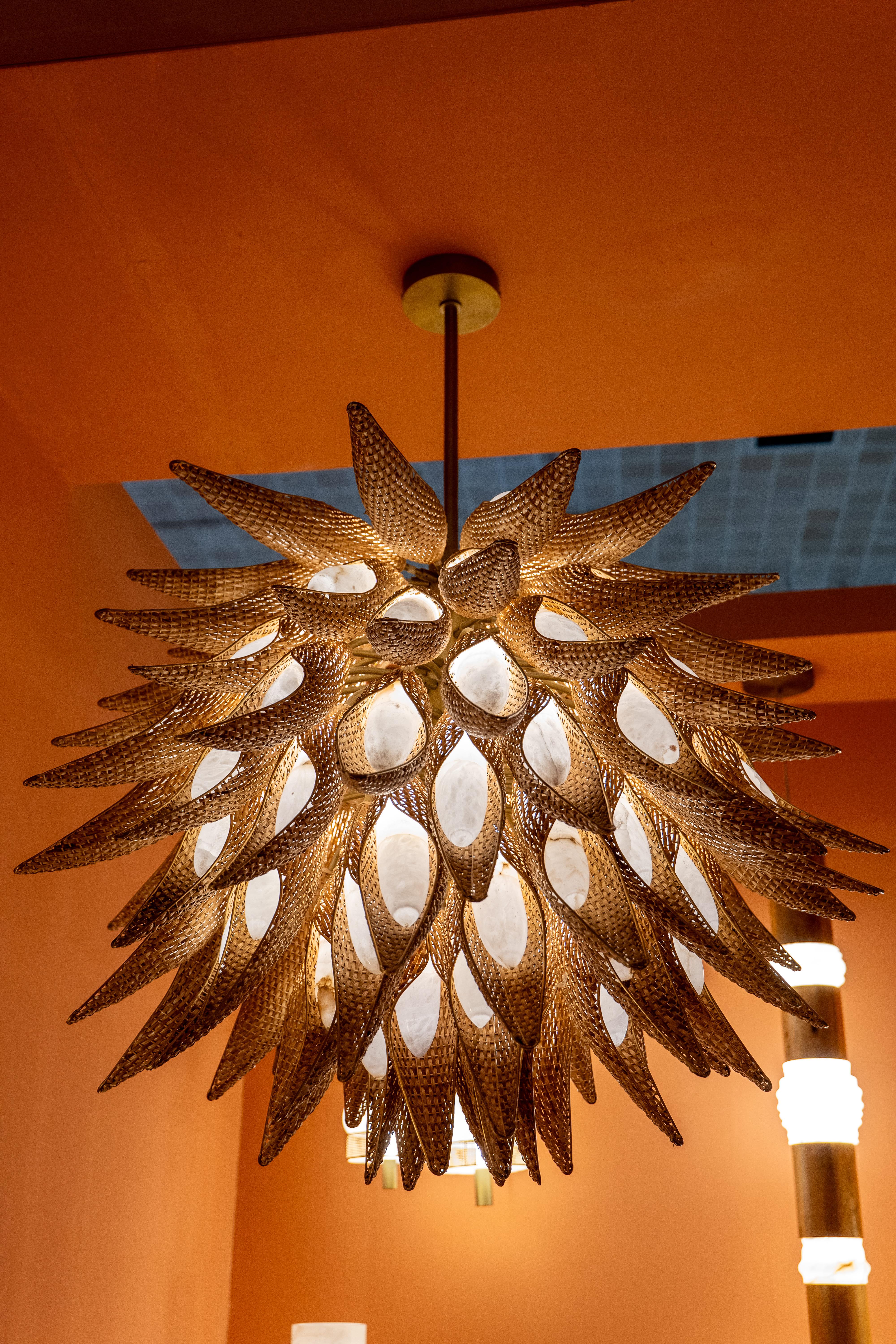 Add an exotic statement piece to your space with this intricately designed chandelier, inspired by organic forms and natural textures. Resembling a blooming flower or a burst of feathers, this chandelier is handcrafted with precision, featuring