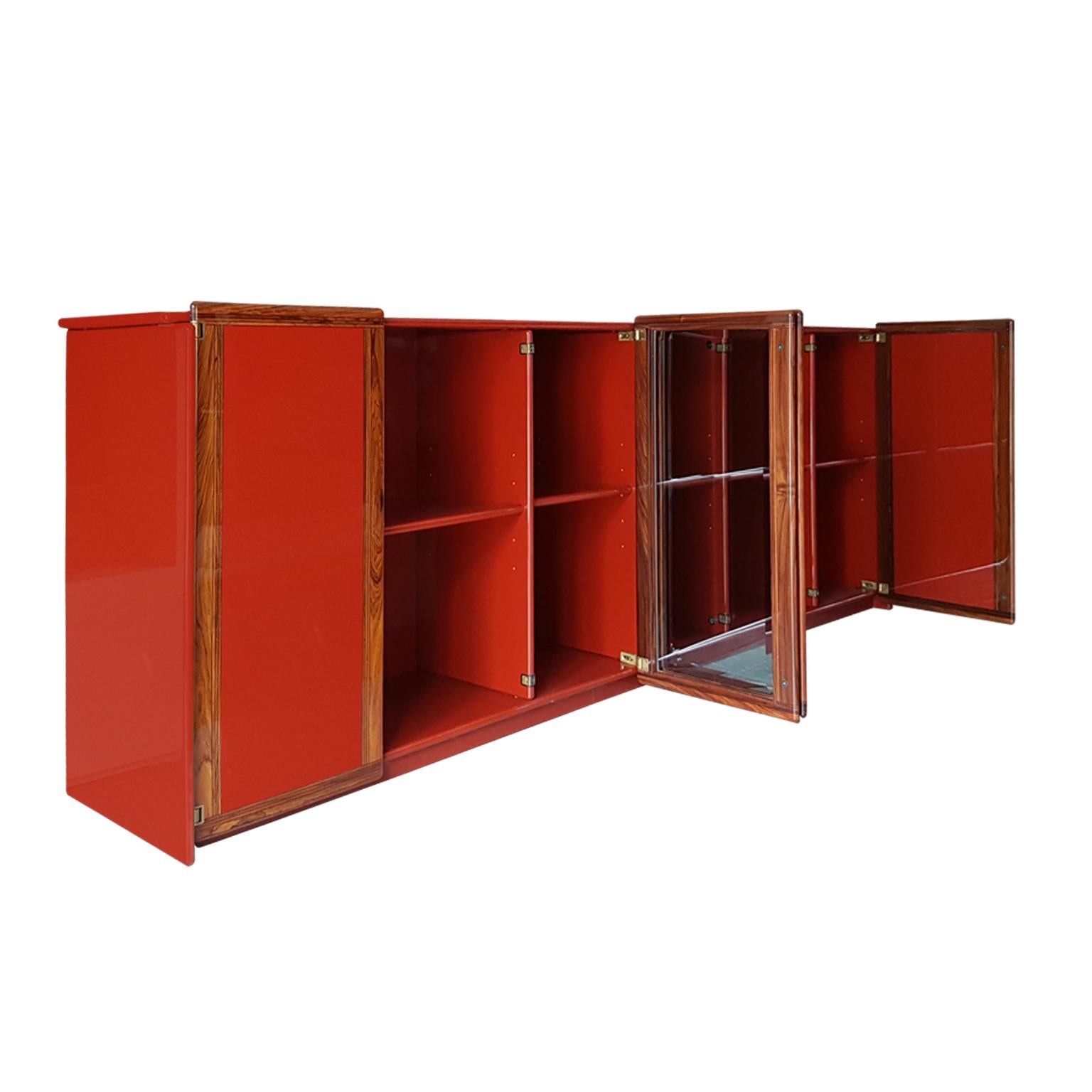 New Harmony Collection Sideboard. Unit made in bright polyester red lacquered wood with two doors in bevelled crystal glass with edges in solid rosewood with strips of contrasting harwood inlays, transparent bright polyester finish.
Adjustable